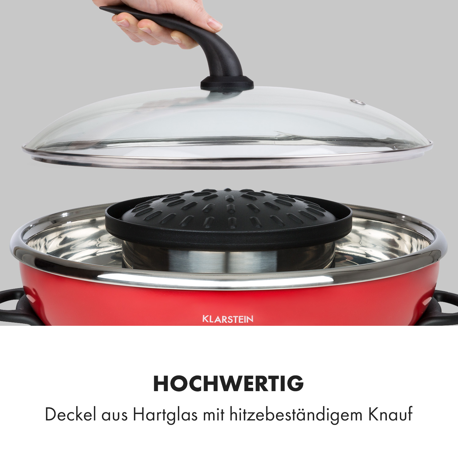 Rotes und silbernes Kochgerät mit Glasdeckel und schwarzem Griff.