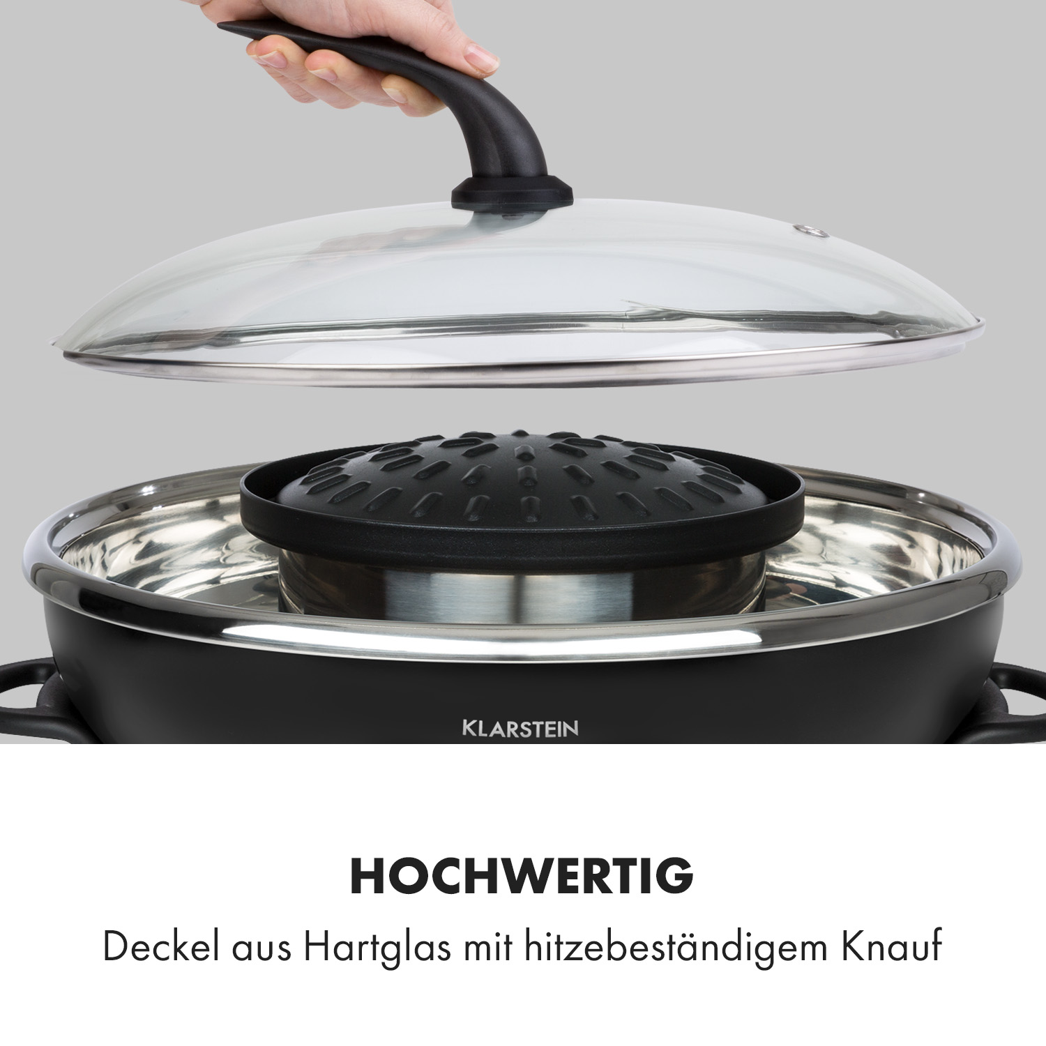 Ein schwarzer Kochtopf mit Glasdeckel. Der Topf hat eine schwarze Mitte. Ein weißer Hintergrund wird verwendet.