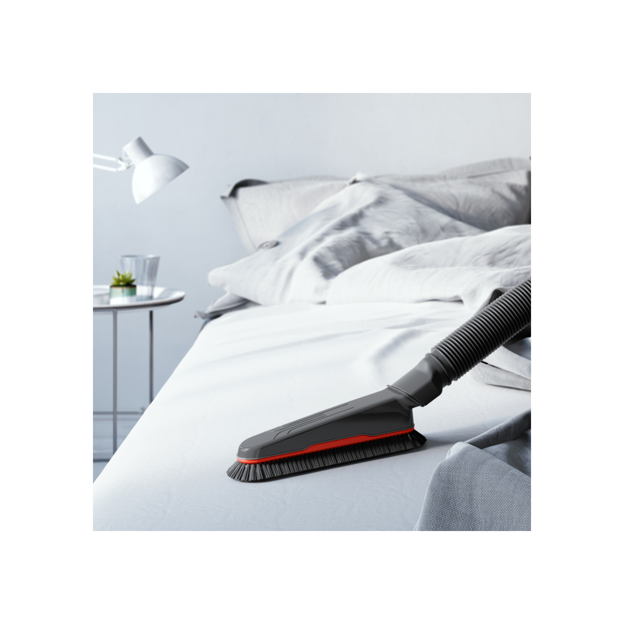Testa dell'aspirapolvere su un letto. Il letto ha lenzuola bianche. Una lampada e un tavolo sono sullo sfondo.