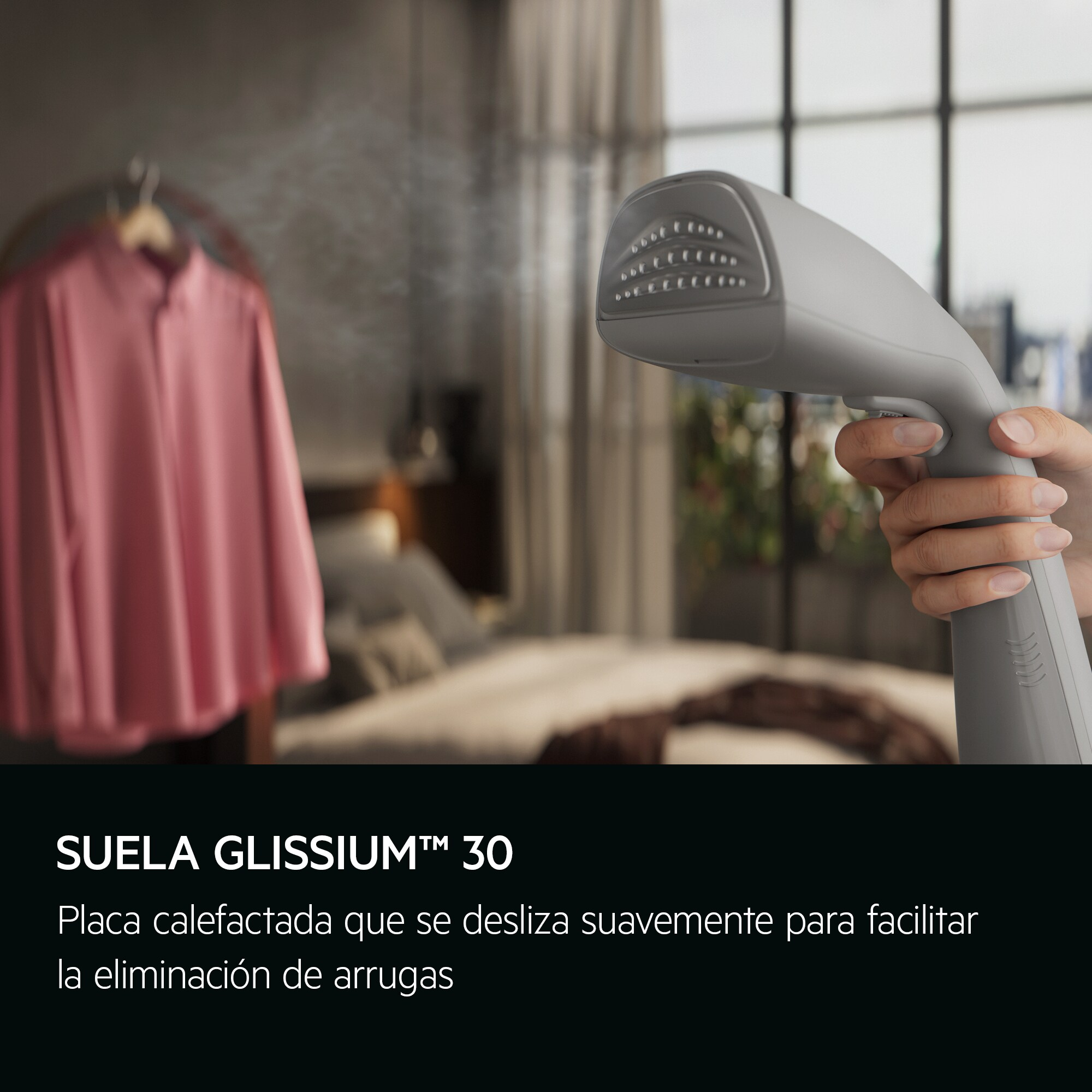 Mano sosteniendo un vaporizador gris sobre camisa rosa, con fondo.