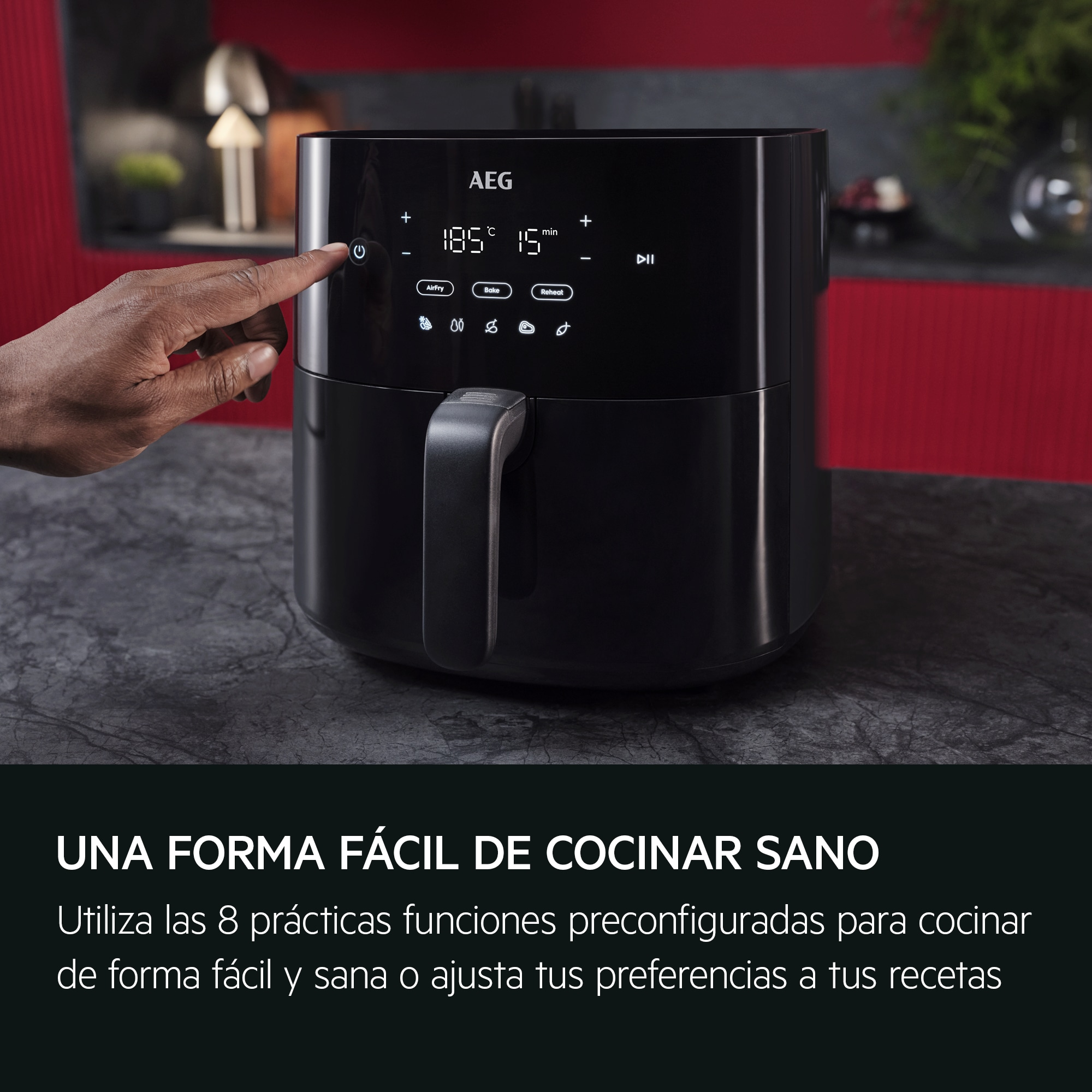 Friggitrice ad aria nera con una mano che preme un pulsante sul pannello di controllo, su una superficie scura.