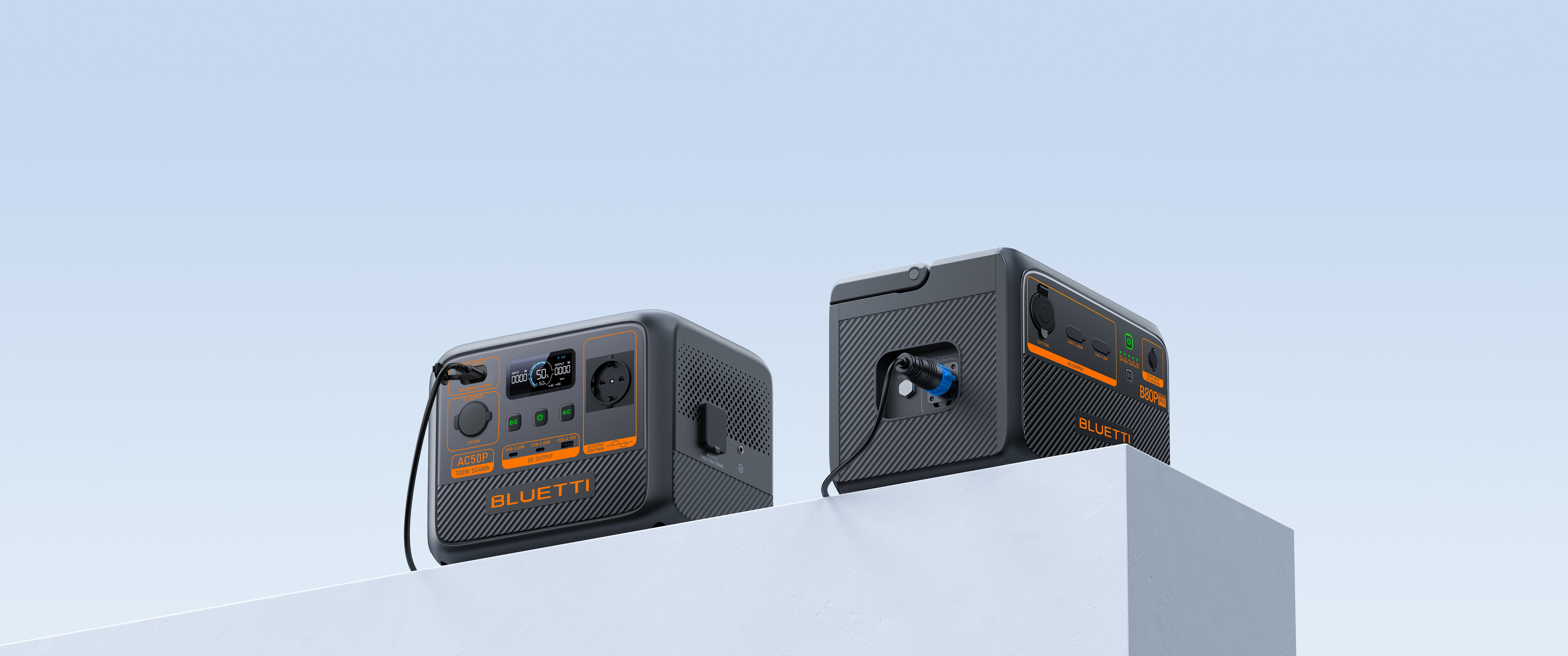 Dwie czarno-pomarańczowe elektrownie na białym bloku na tle niebieskiego gradientu.