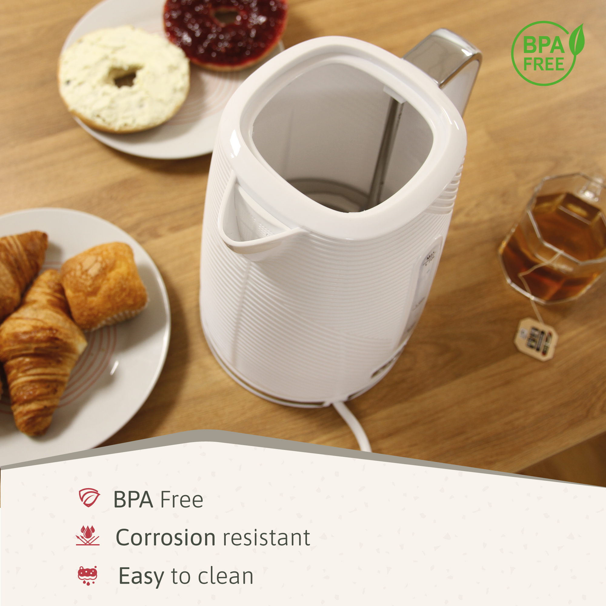 Hervidor eléctrico blanco con comida en platos al lado. Sin BPA, resistente a la corrosión y fácil de limpiar.