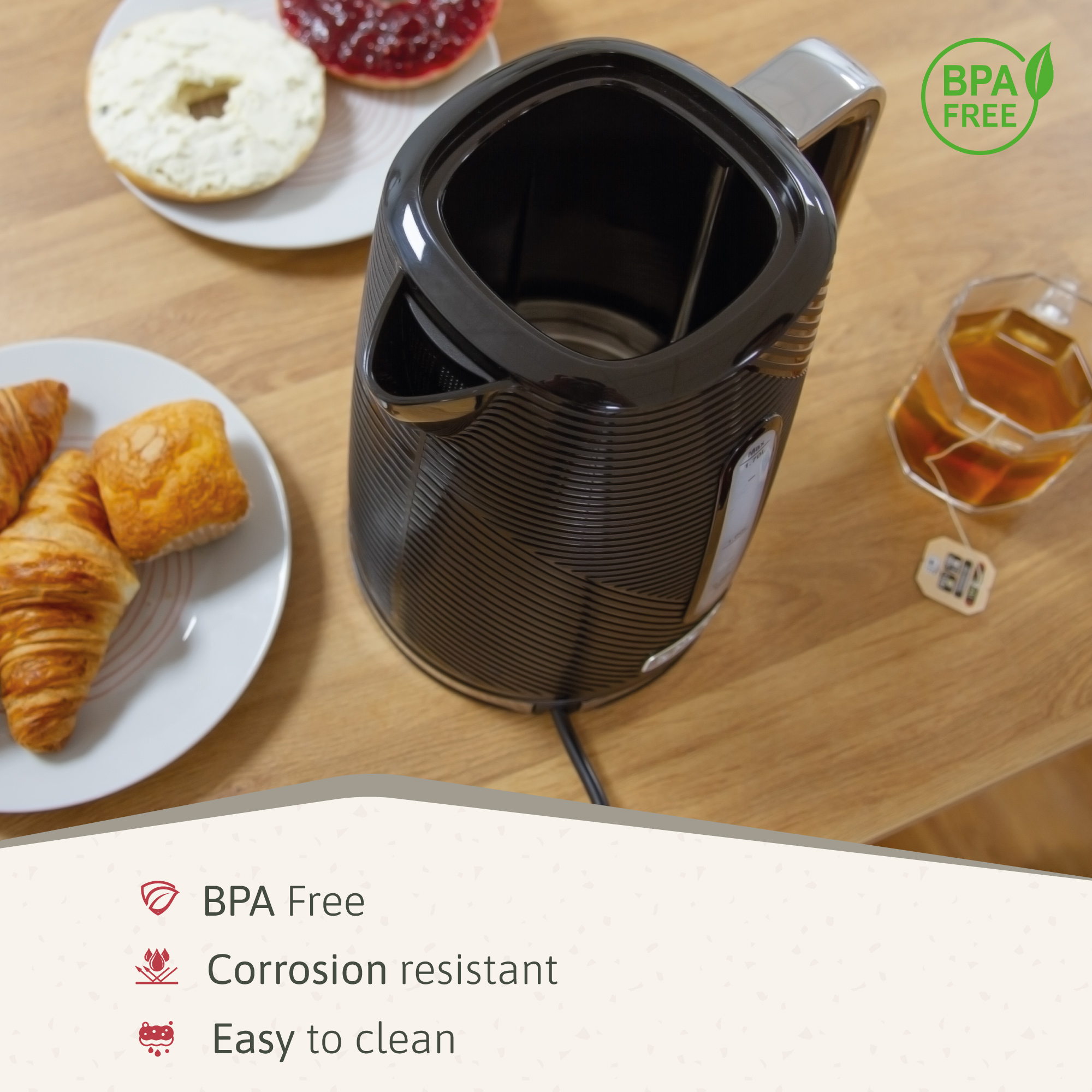 Hervidor eléctrico negro con té y pasteles en una mesa de madera, con etiqueta sin BPA.