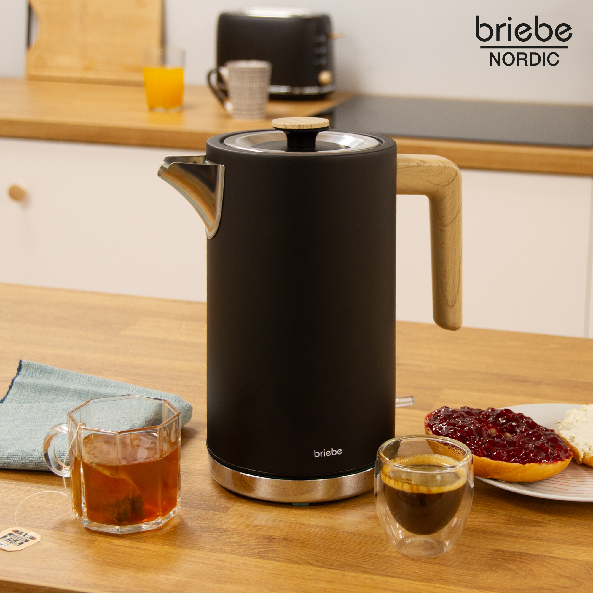 Una tetera eléctrica negra con un mango de madera y un vaso de té y café. Un logo de Briete.