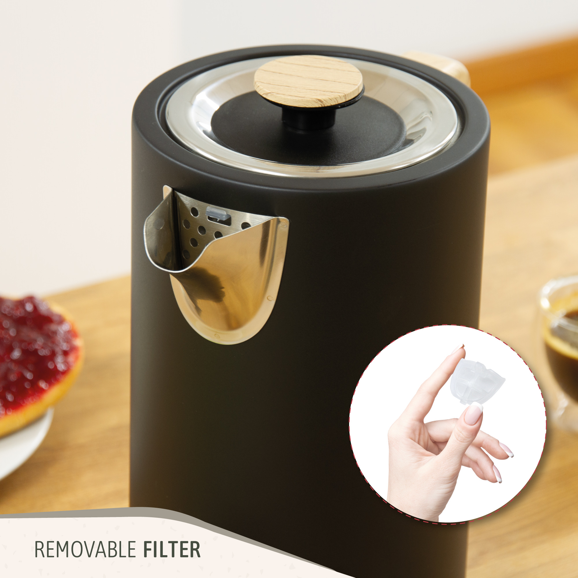 Una tetera negra con filtro extraíble y una mano sosteniendo un cubo de hielo.