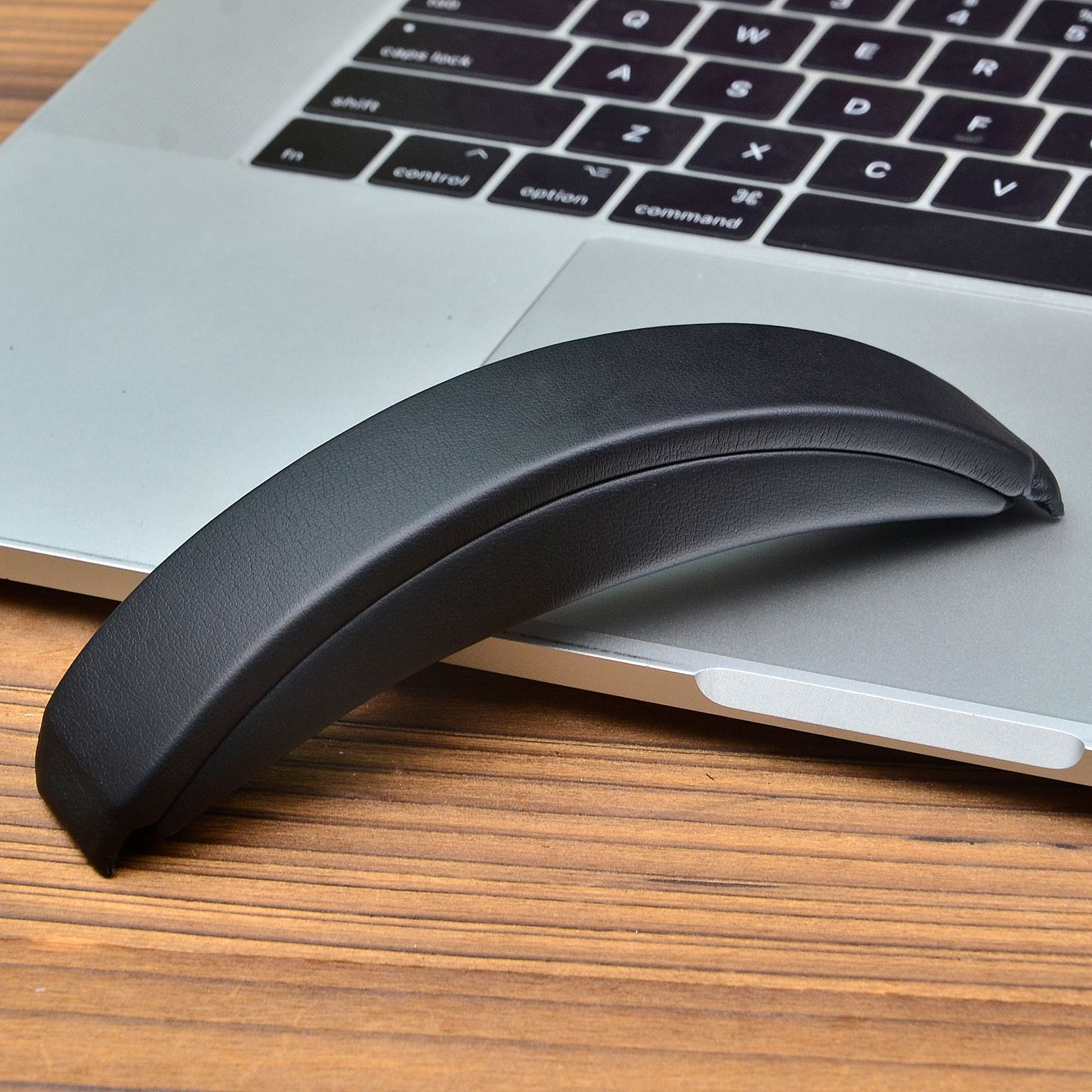 Czarna podpórka pod nadgarstek na klawiaturze laptopa. Podpórka jest zakrzywiona.