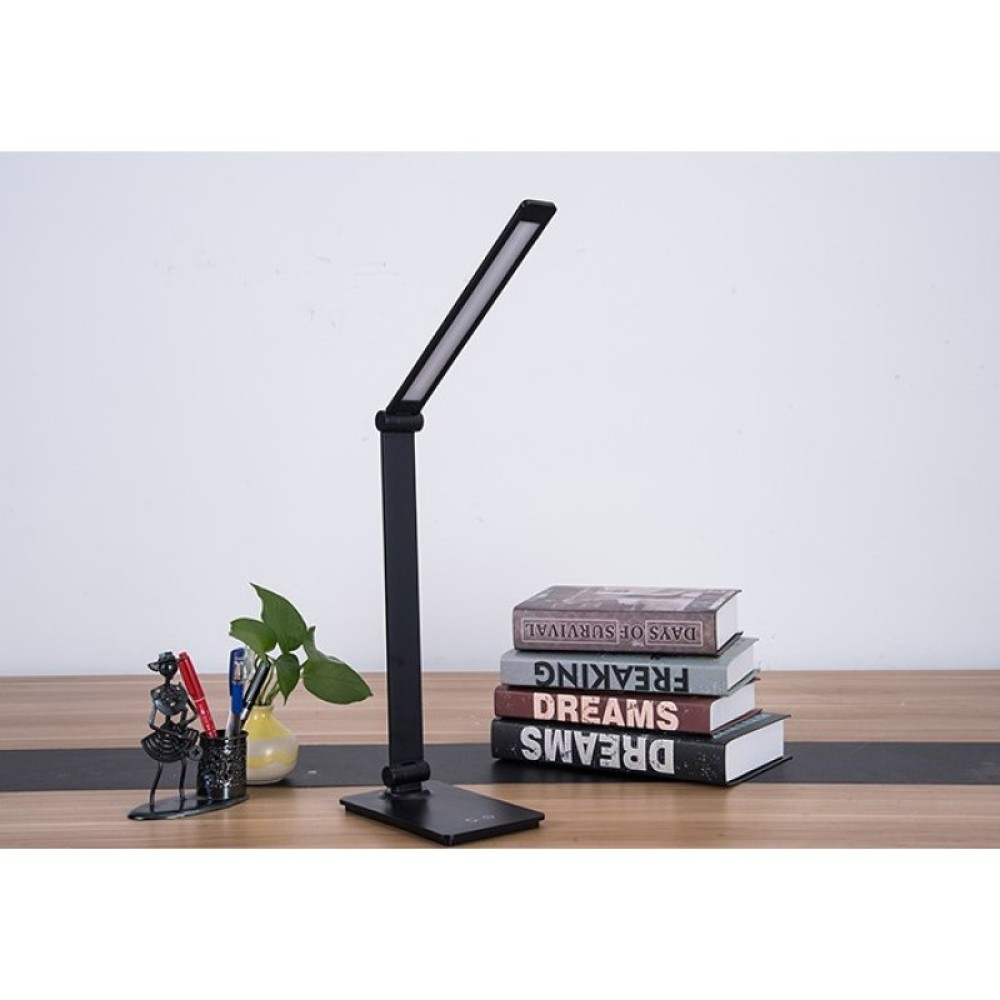 Eine schwarze LED-Schreibtischlampe auf einem Schreibtisch mit Büchern, Stiften.