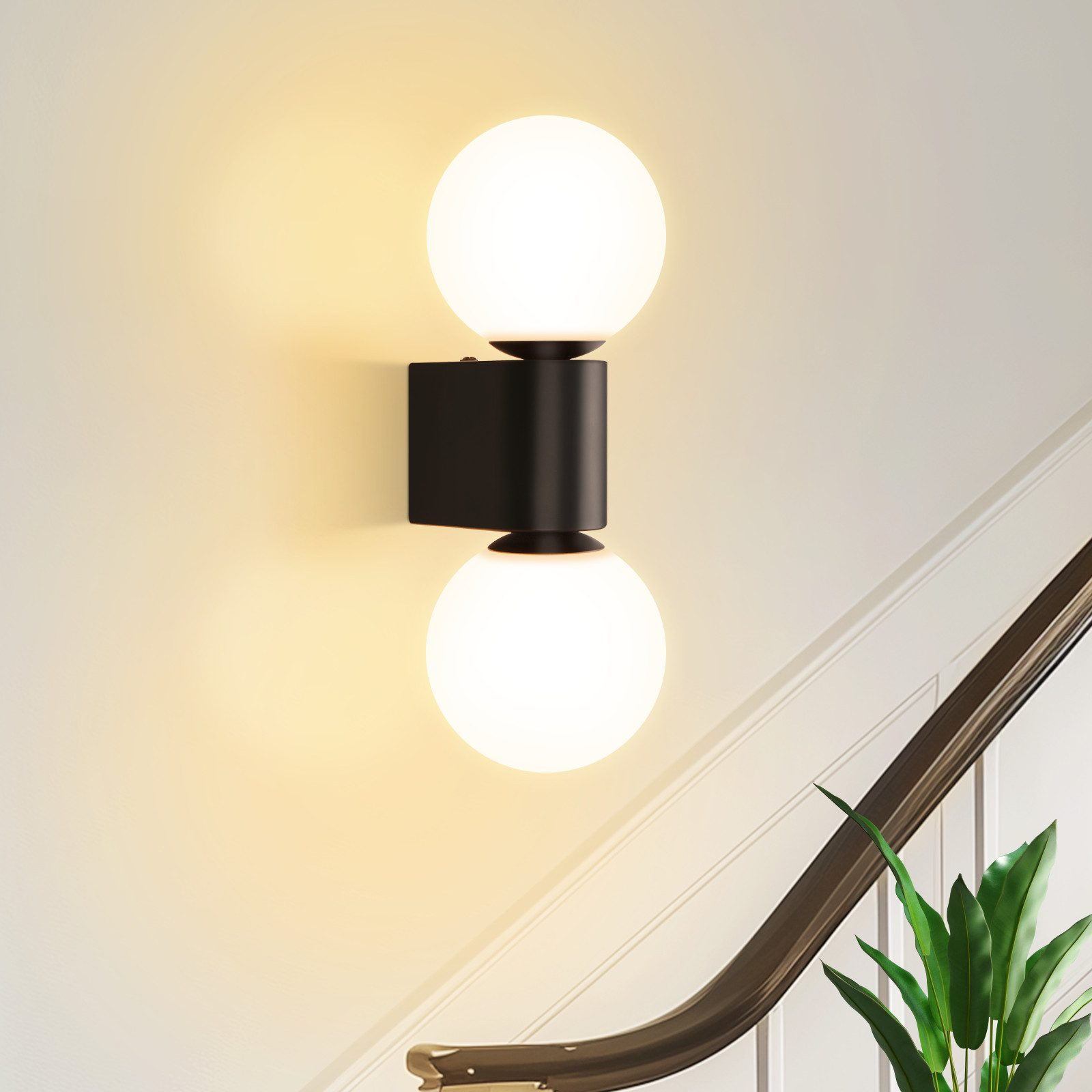 Applique con due luci a globo bianche su base nera, montata su una parete e scala beige.