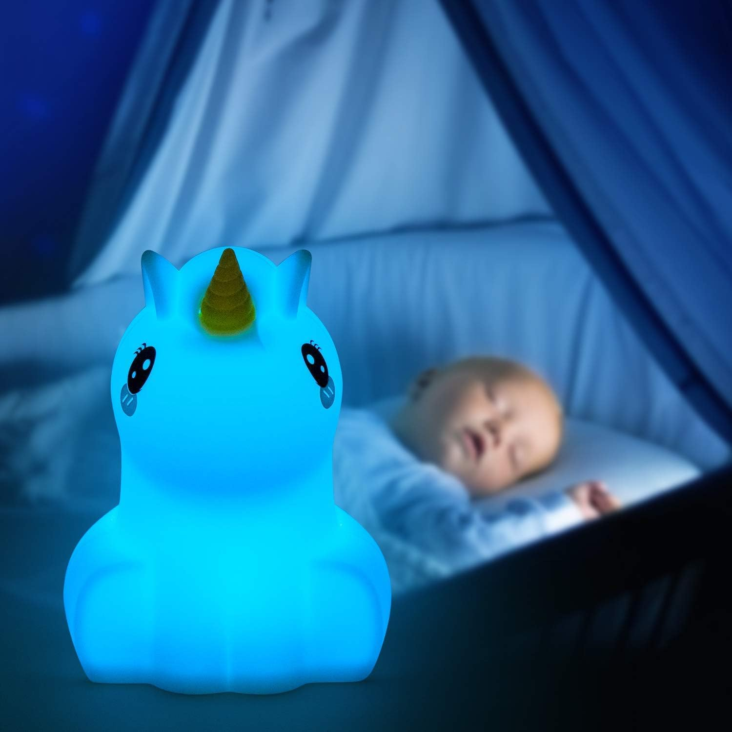 Blaues Einhorn-Nachtlicht neben einem schlafenden Baby in einem Kinderbett.
