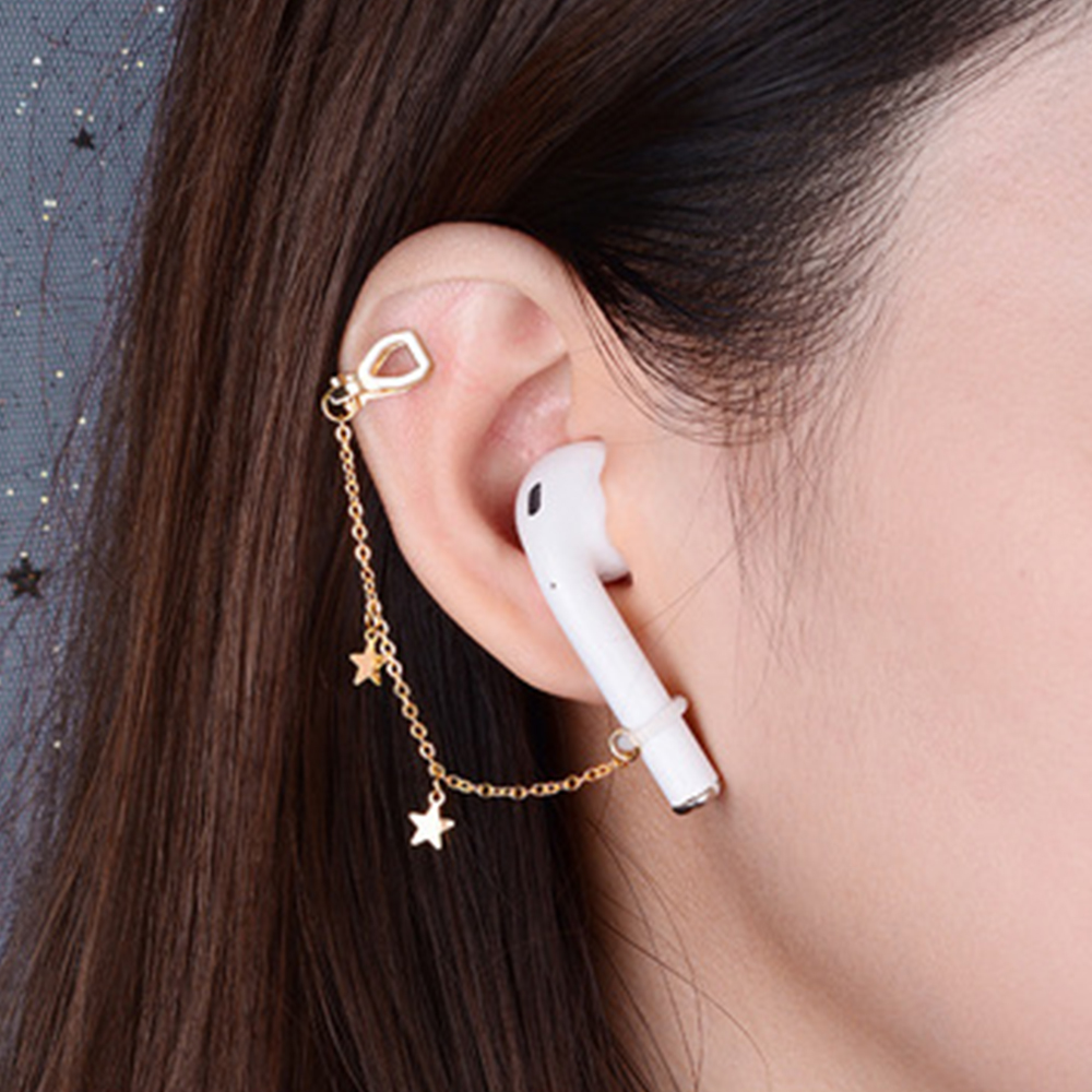 Ein Ohr mit einem AirPod und einer goldenen Kette mit Sternen. Ohrhörer mit Goldkette.