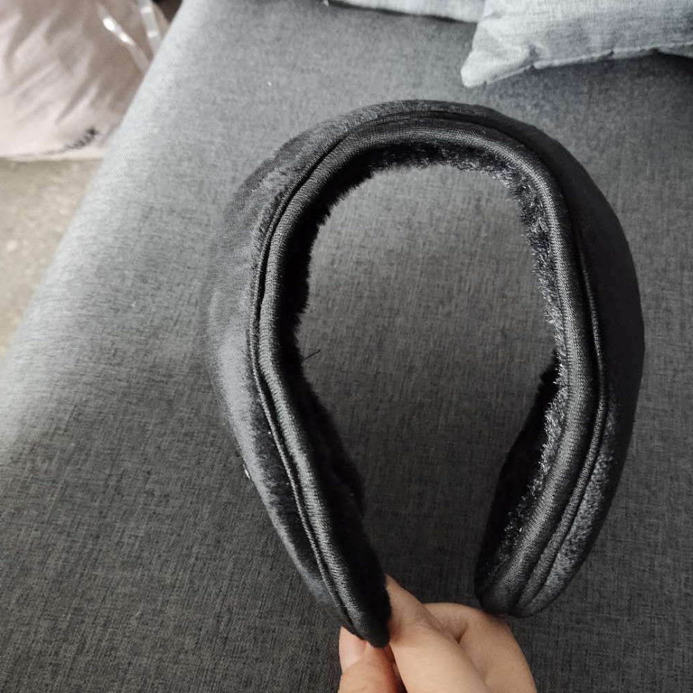 Schwarze Ohrenschützer auf einer grauen Couch, gehalten von einer Hand.