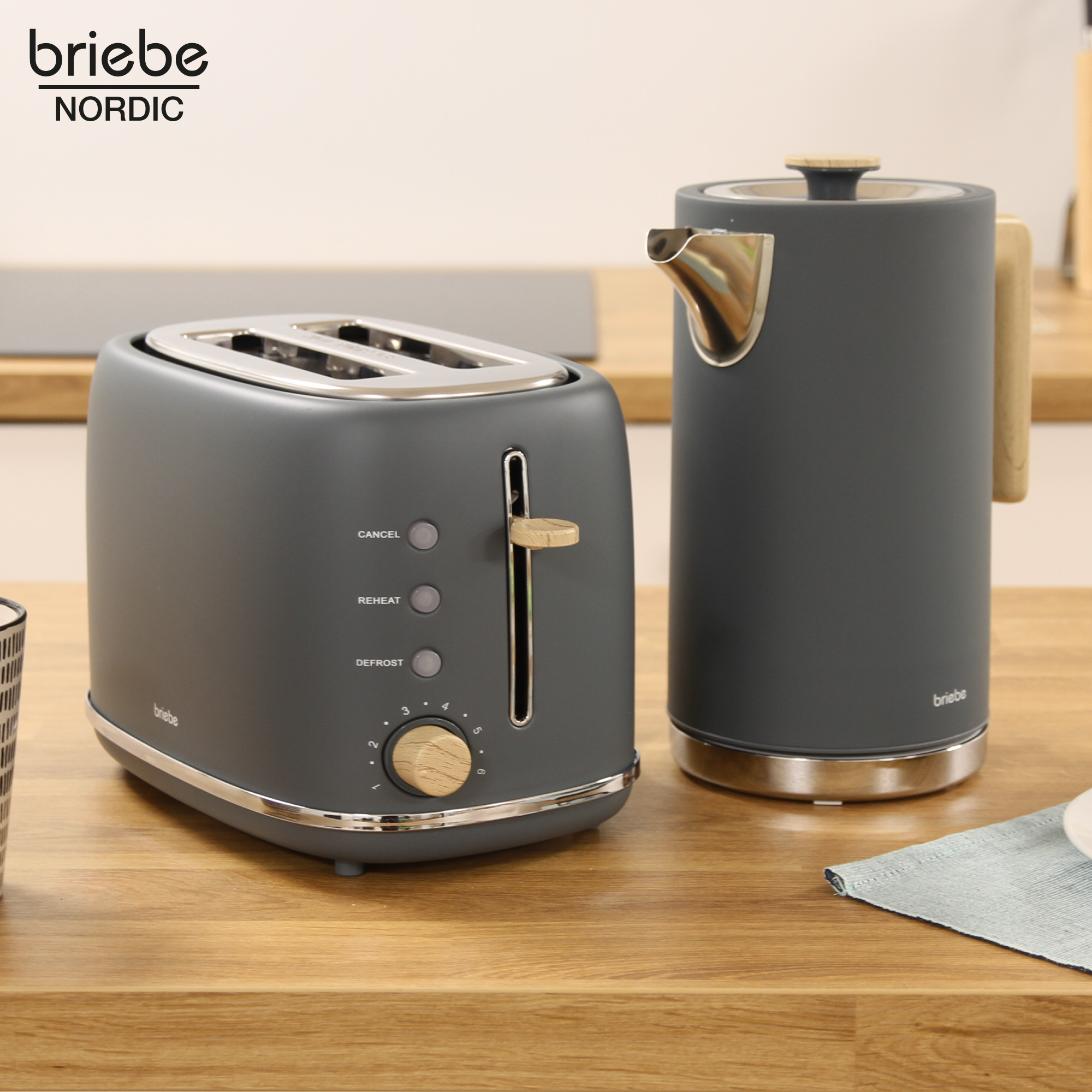Ein Toaster und ein Wasserkocher auf einer Holzoberfläche. Beide Geräte sind dunkelgrau.