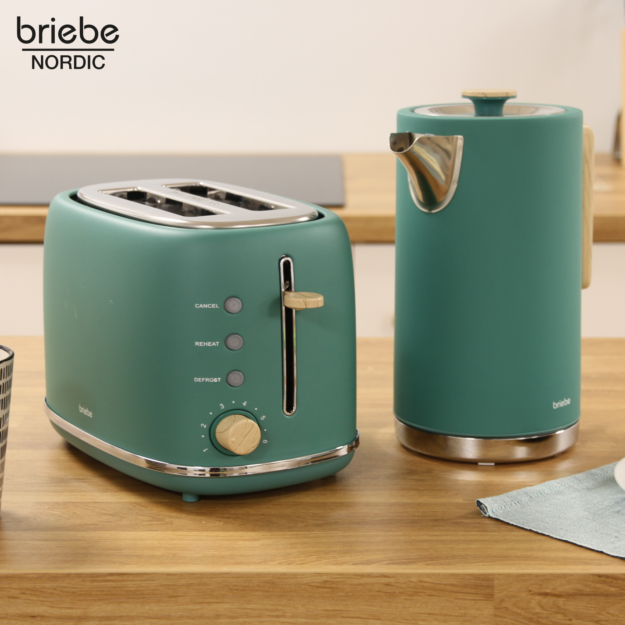 Grüner Toaster und Wasserkocher auf Holzoberfläche. Der Toaster hat Einstellungen für Abbruch, Aufwärmen, Auftauen.