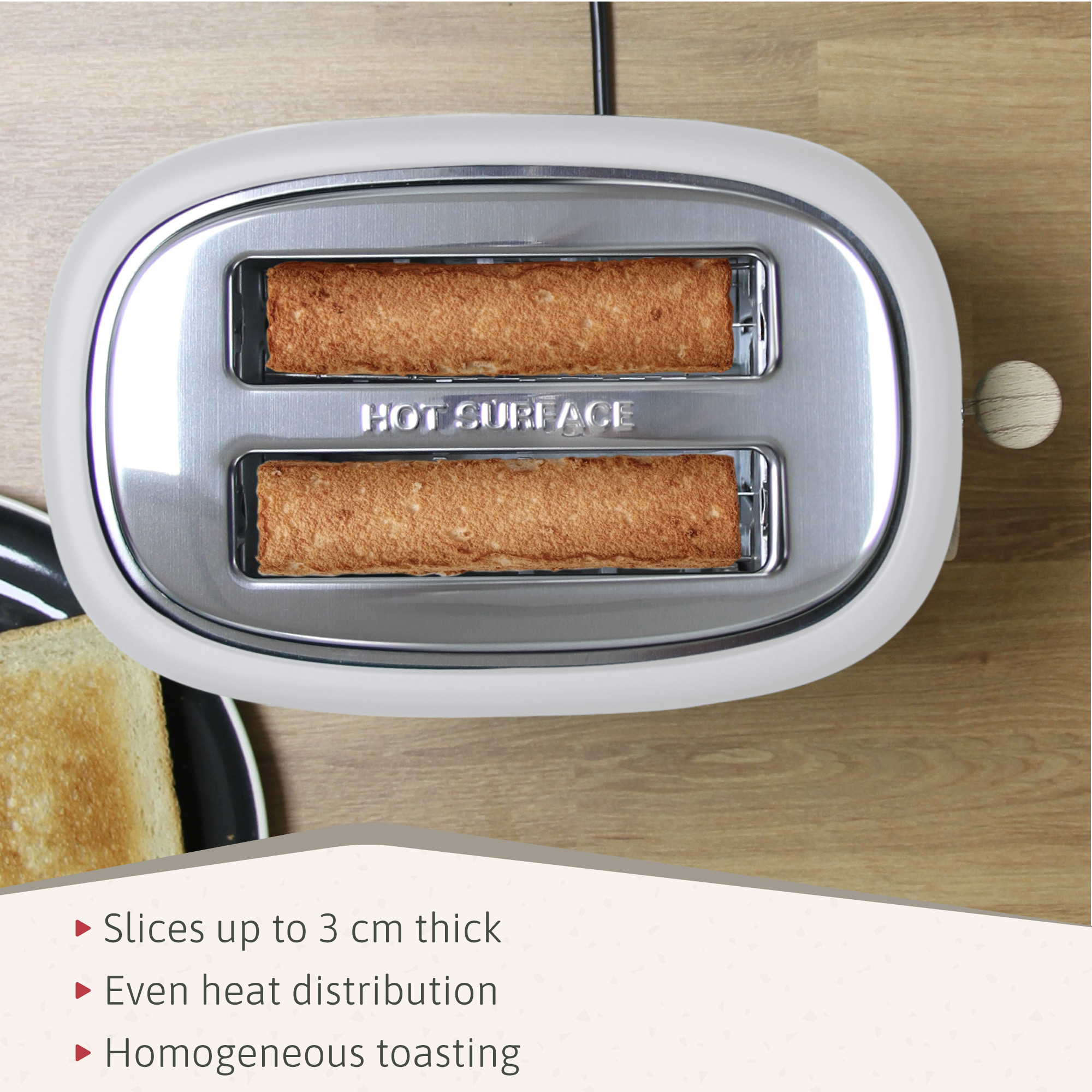 Ein weißer Toaster mit zwei Brotscheiben. Das Wort "HOT SURFACE" ist sichtbar.