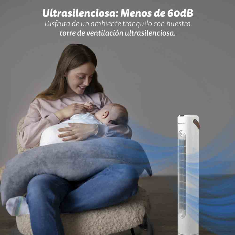 Kobieta karmiąca piersią dziecko siedząc na krześle obok wentylatora wieżowego.