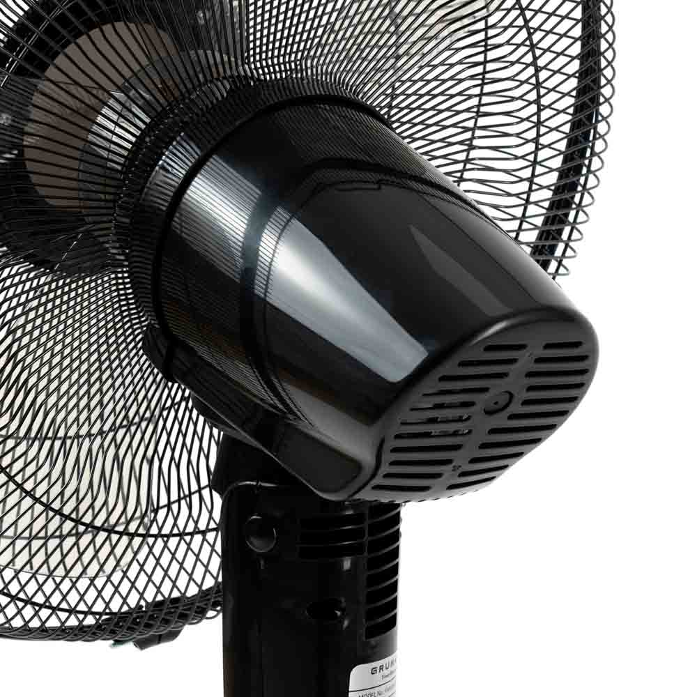 Primer plano de un ventilador eléctrico negro con rejilla protectora y carcasa negra.