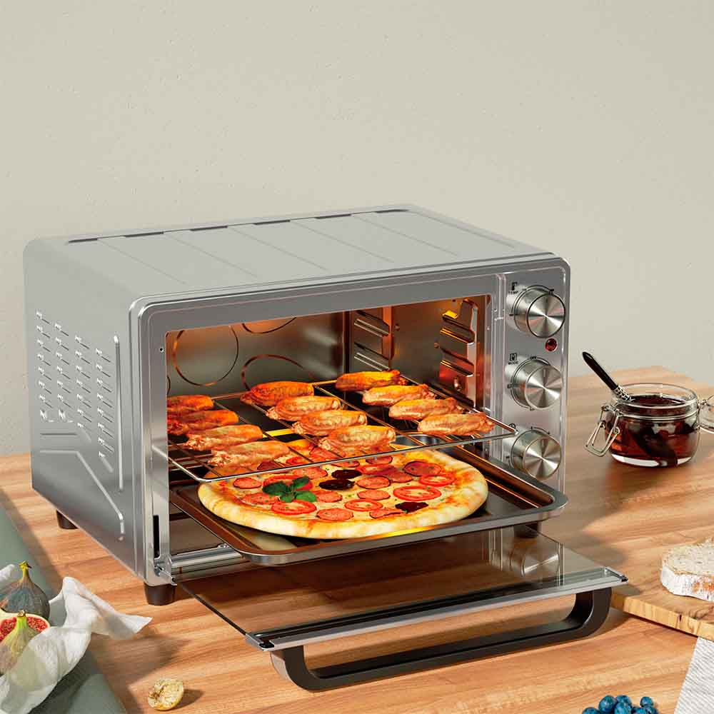 Un horno plateado con pizza y productos horneados. Está en una mesa de madera con ingredientes.