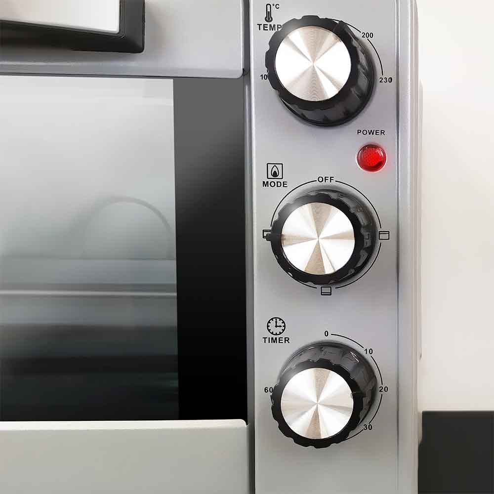 Primo piano del pannello di controllo del forno con manopole per temperatura, modalità e timer e luce rossa.