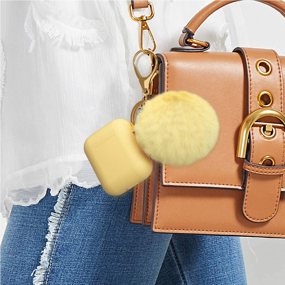 Ein gelbes Etui mit einem Pompon, das an einer Handtasche befestigt ist. Die Handtasche ist braun und hat einen goldenen Verschluss und einen Riemen.