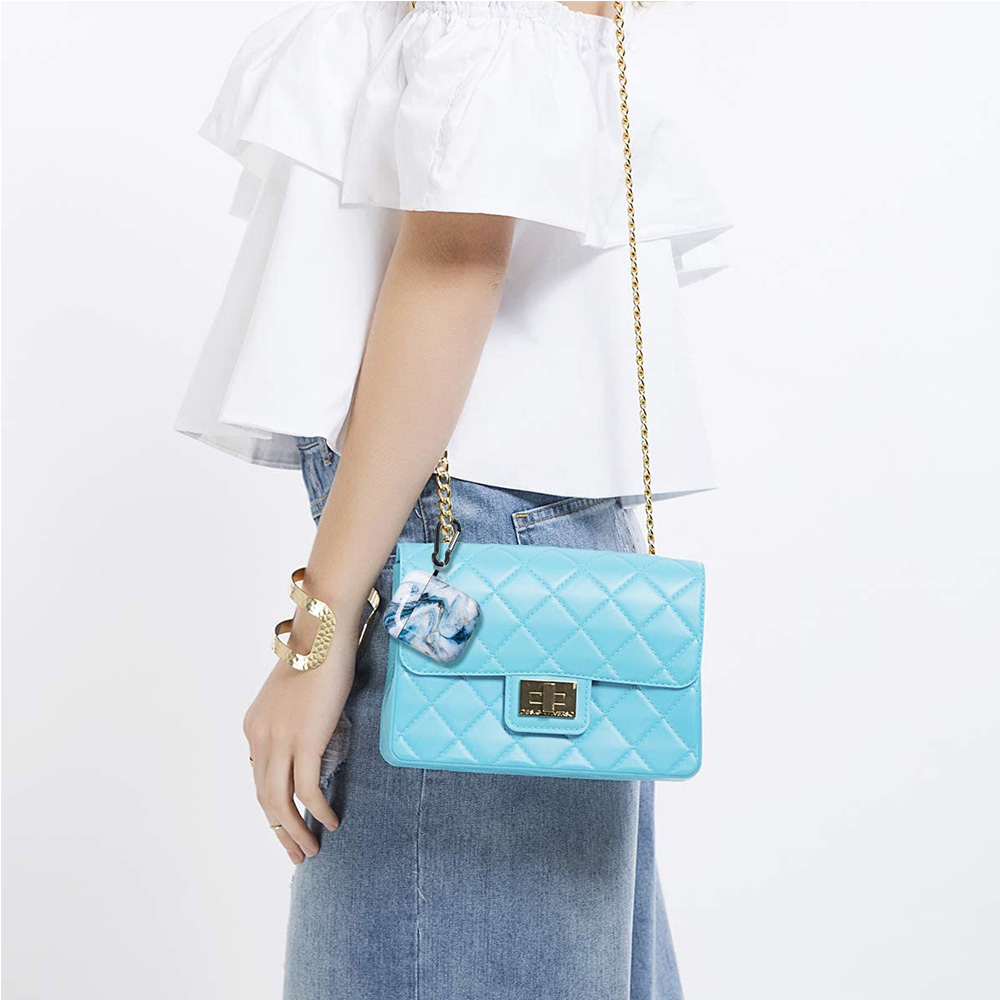 Frau mit blauer gesteppter Handtasche, goldenem Armband und weißem Oberteil.