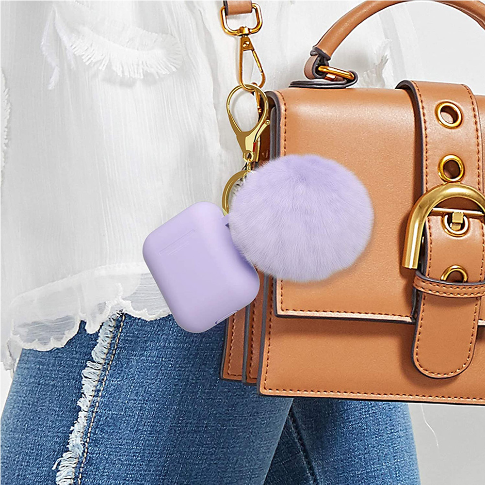 Ein lila AirPod-Etui mit einem passenden Pompon-Schlüsselanhänger, der an einer hellbraunen Ledertasche hängt.