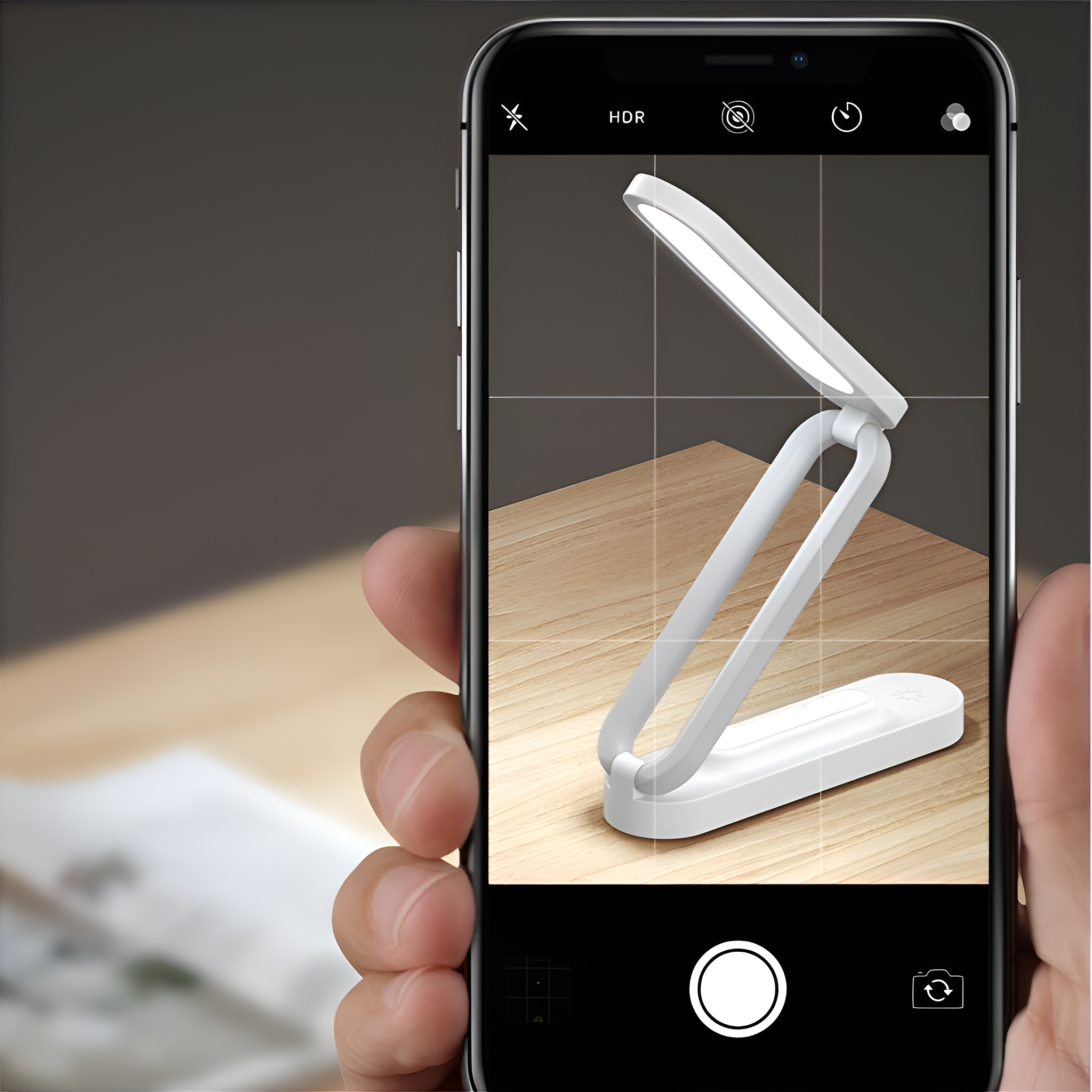Ein Telefon, das ein Foto einer weißen Lampe auf einem Holztisch macht.