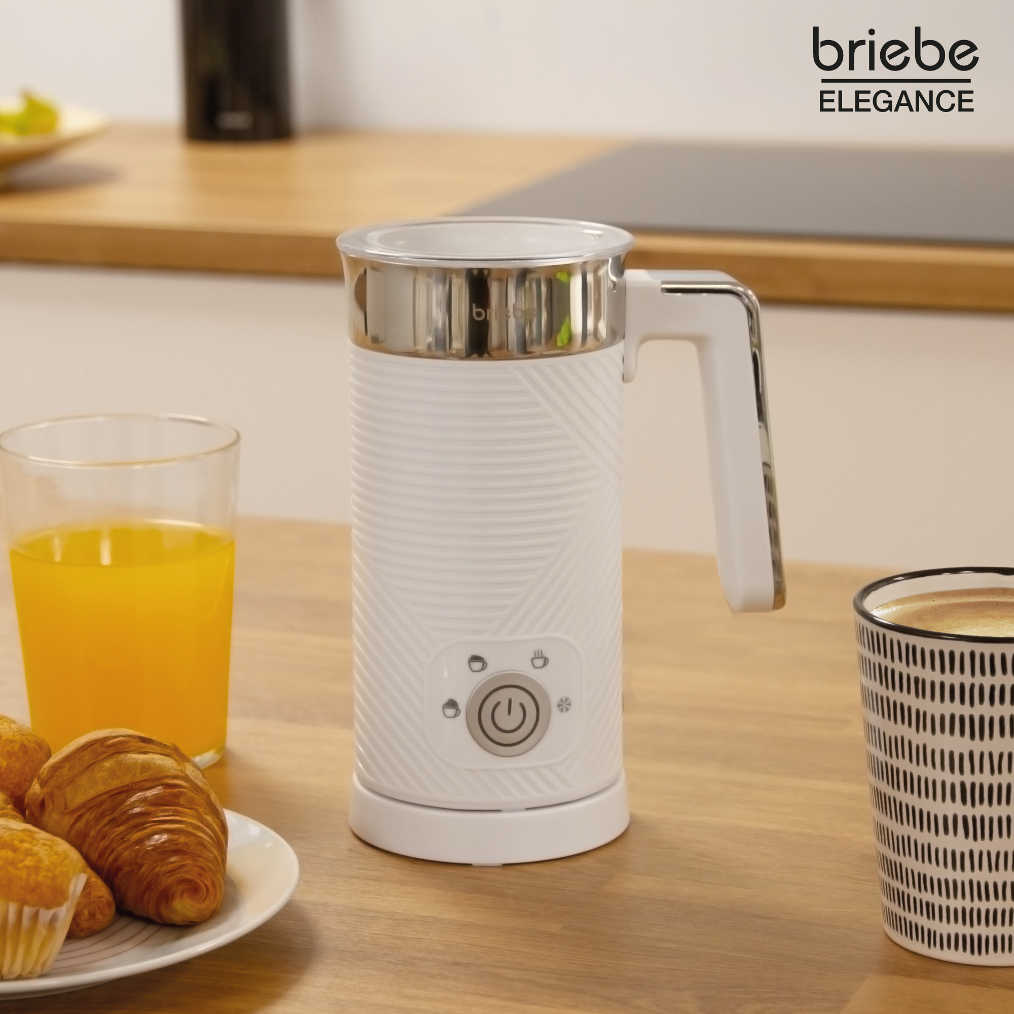 Weißer Milchaufschäumer mit Griff, Glas Saft, Gebäck und Kaffeetasse auf Holzoberfläche.