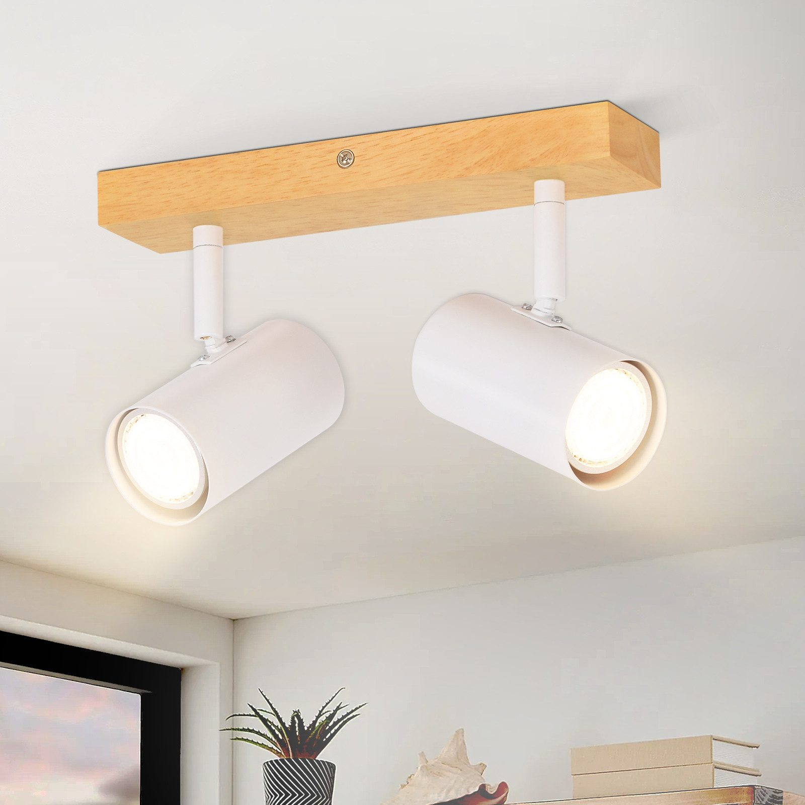 Due faretti bianchi attaccati a una trave di legno, montati su un soffitto bianco.