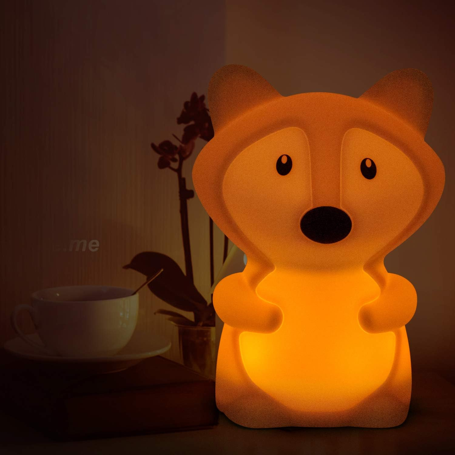 Fuchs-Nachtlicht, orange leuchtend. Im Hintergrund Tasse und Blumen.