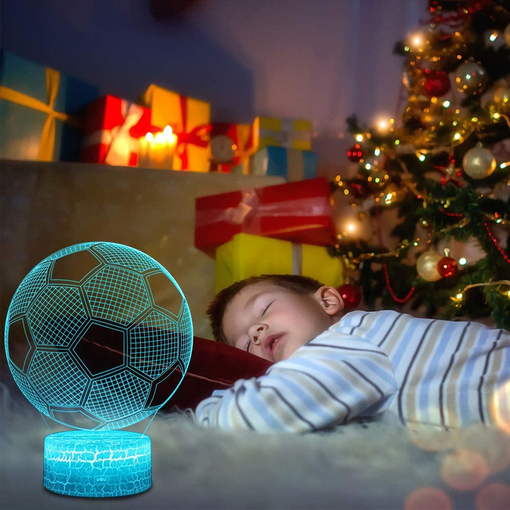 Schlafendes Kind neben einer Fussball-Lampe mit Weihnachtsbaum im Hintergrund.