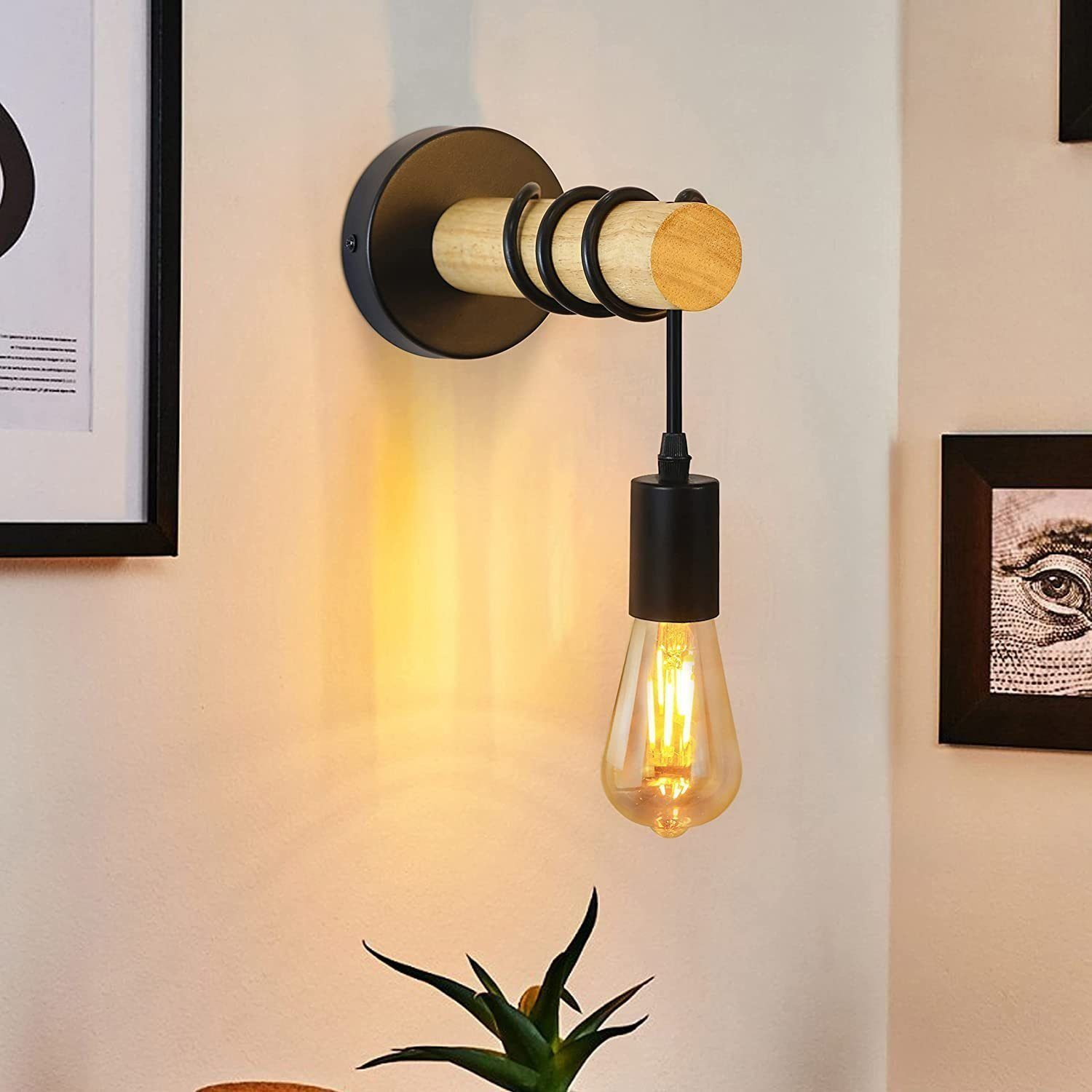 Applique da parete con elementi in legno e neri, che tiene una lampadina accesa. Ci sono alcune cornici intorno.