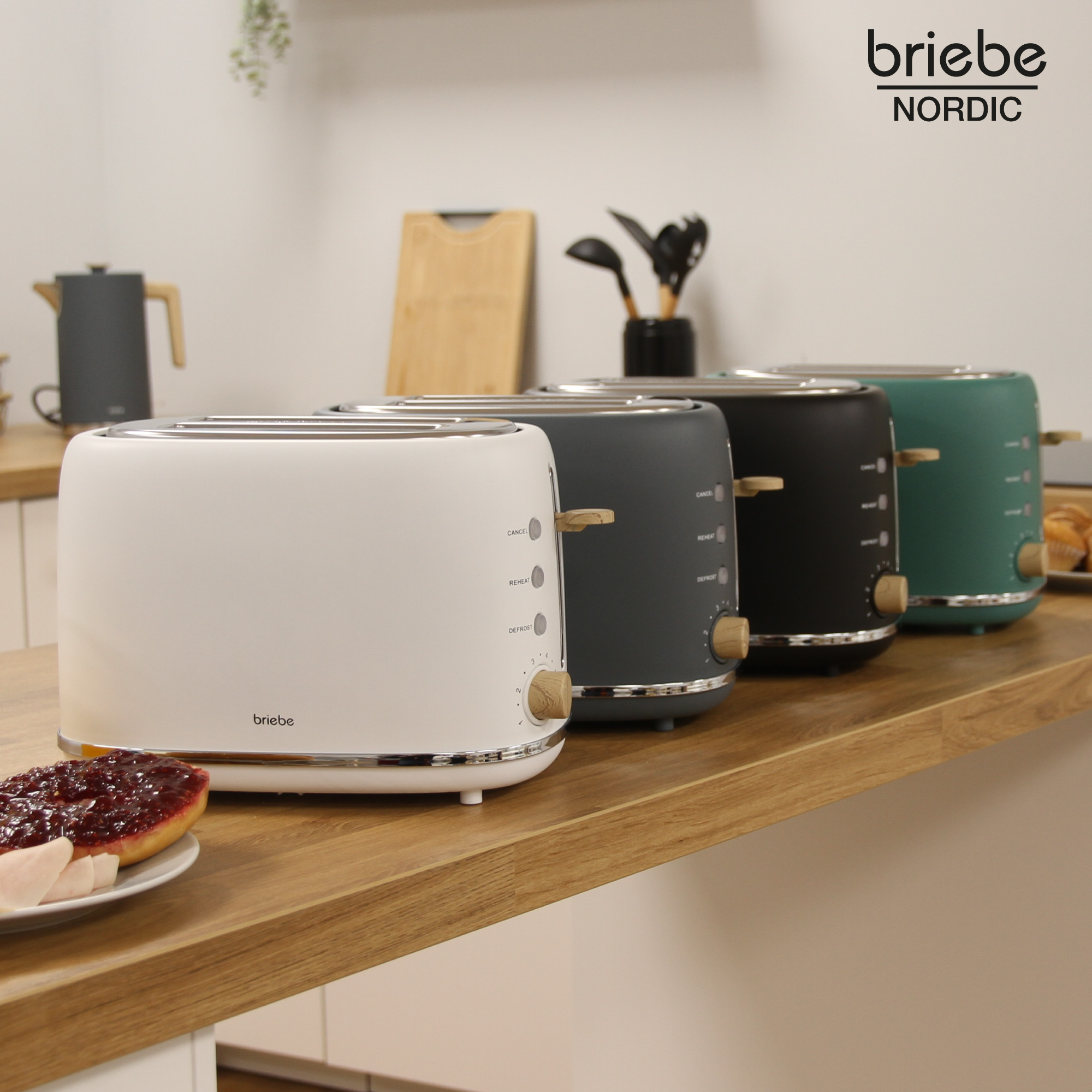 Vier Toaster in einer Reihe auf einer Holztheke. Jeder Toaster hat eine andere Farbe: Weiß, Grau, Schwarz und Grün.