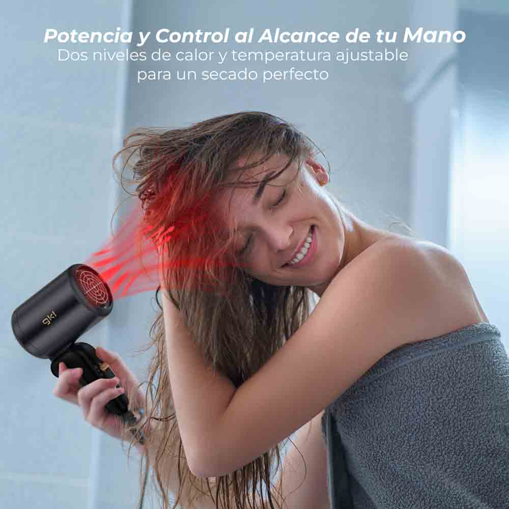 Una mujer usa un secador de pelo negro en su cabello. Emite luz roja.