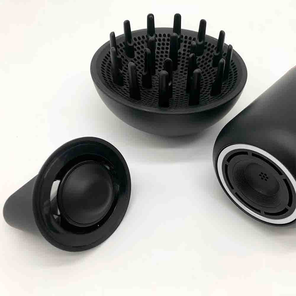 Accessori neri per asciugacapelli su una superficie bianca: un diffusore e due ugelli.