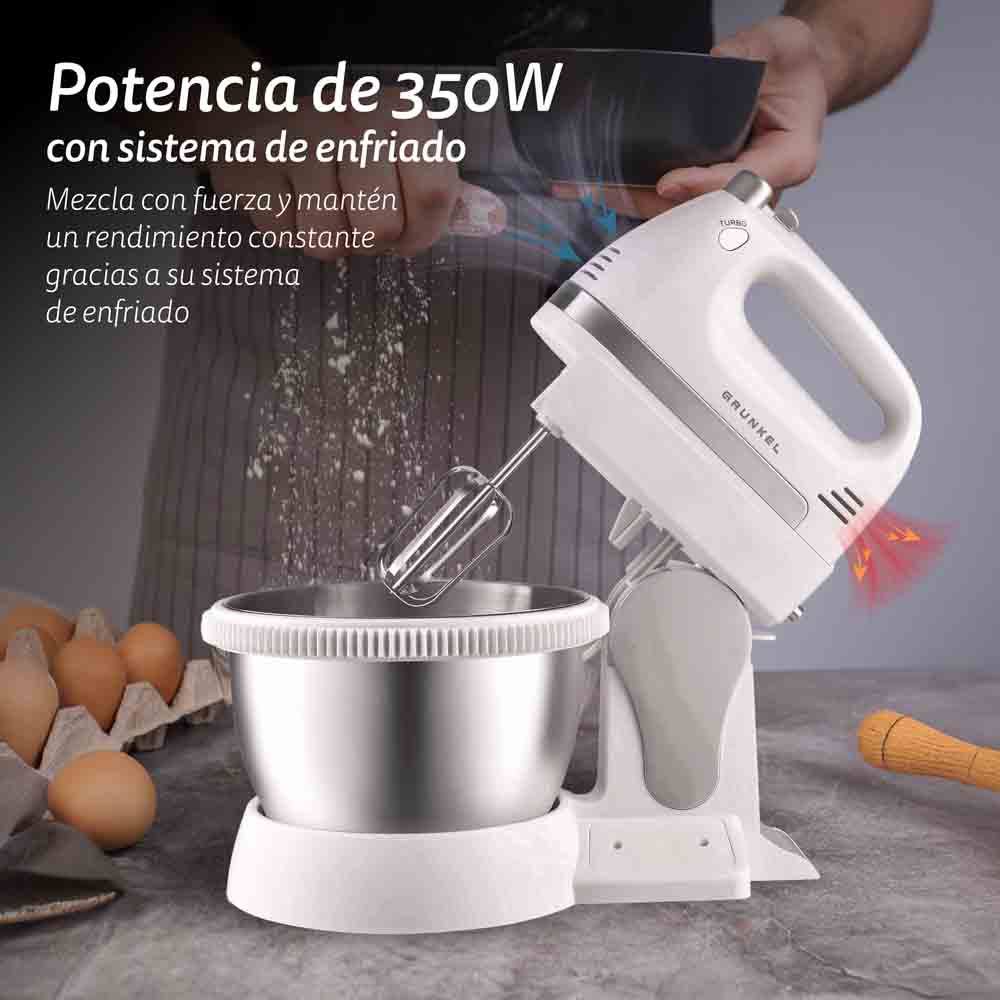 Una batidora de mano blanca con un bol. La batidora mezcla huevos y harina, con huevos en el fondo.