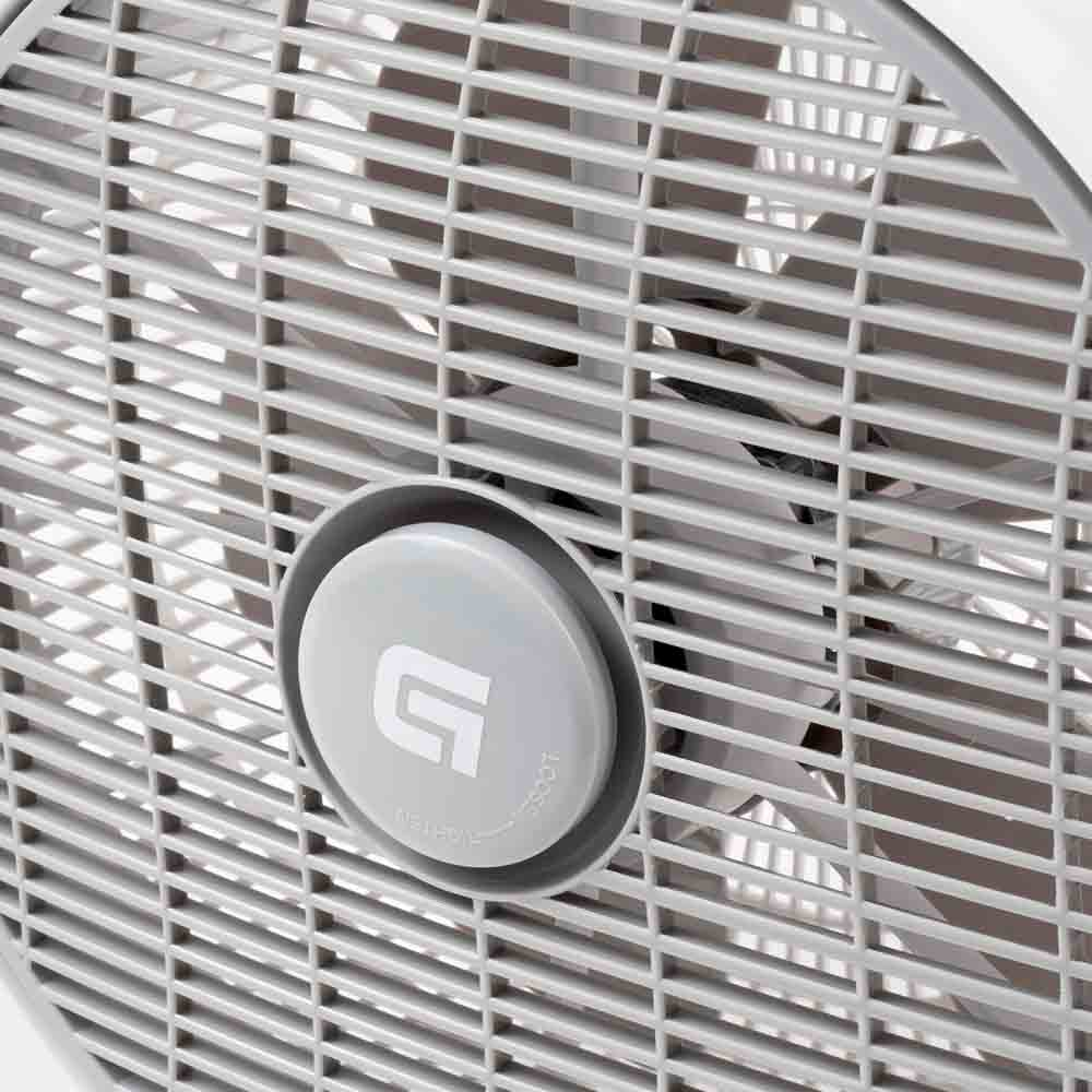 Primer plano de una rejilla de ventilador gris. Una perilla de control circular en el centro.