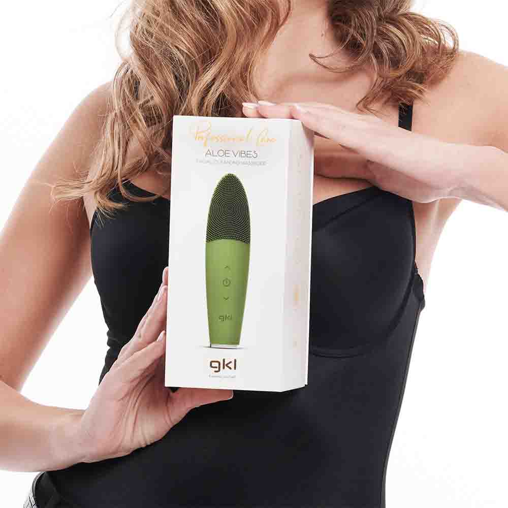 Mujer sosteniendo una caja con un cepillo de limpieza facial. Cepillo y caja verdes visibles.