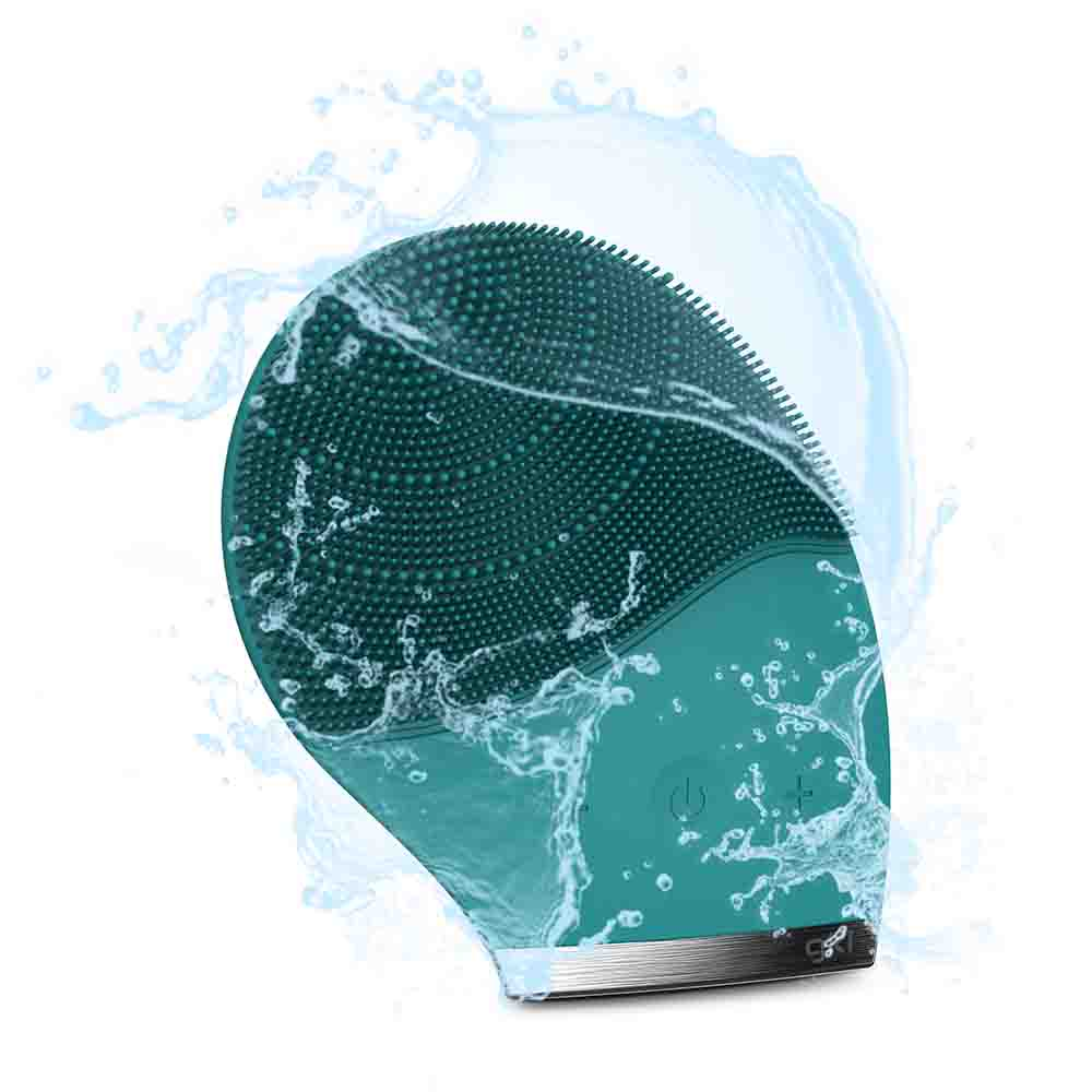 Un cepillo de limpieza facial turquesa con efectos de salpicaduras de agua, aislado sobre fondo blanco. El cepillo está en movimiento.