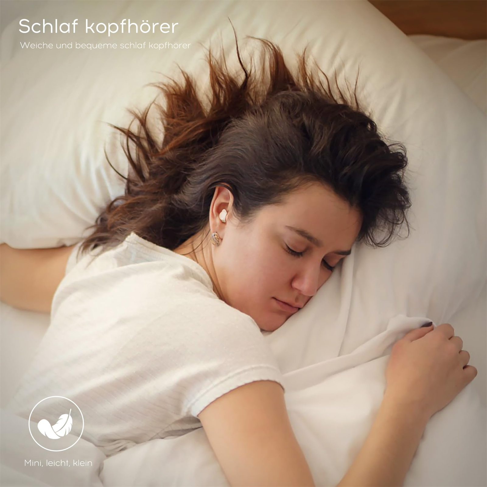 Schlafende Frau mit Kopfhörer. Kopfhörer im Ohr, Frau auf weißem Bett.