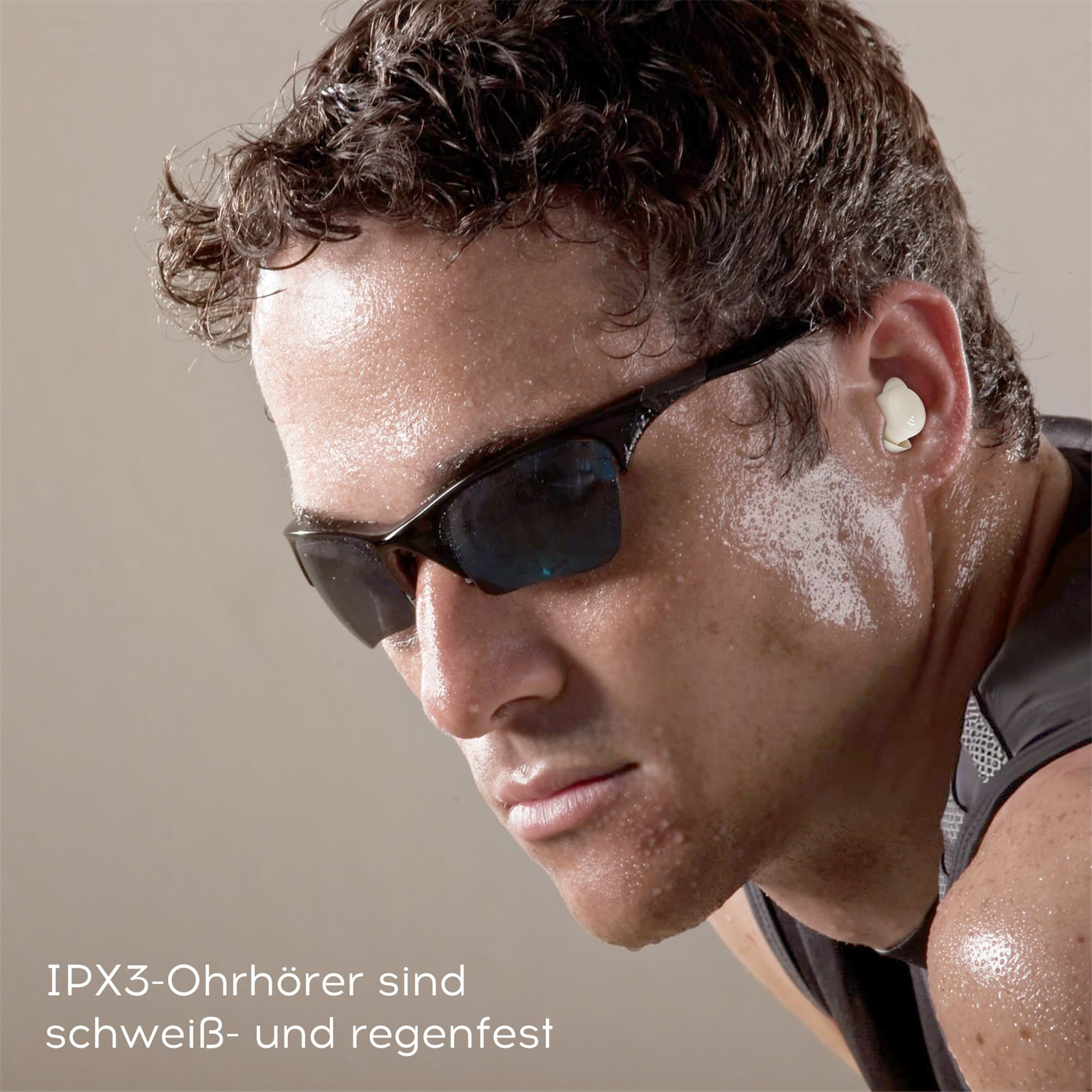 Mann mit Sonnenbrille und Ohrhörern. Schwitzt. Heller Hintergrund.