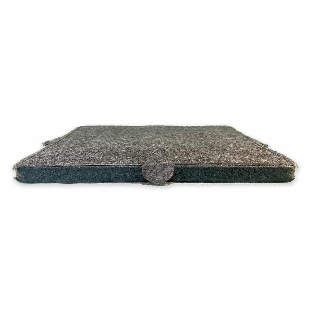 Ein graues Filzpad, das zur Hälfte gefaltet ist. Die Ränder sind dunkelgrün, mit einem grauen Schlaufenverschluss.