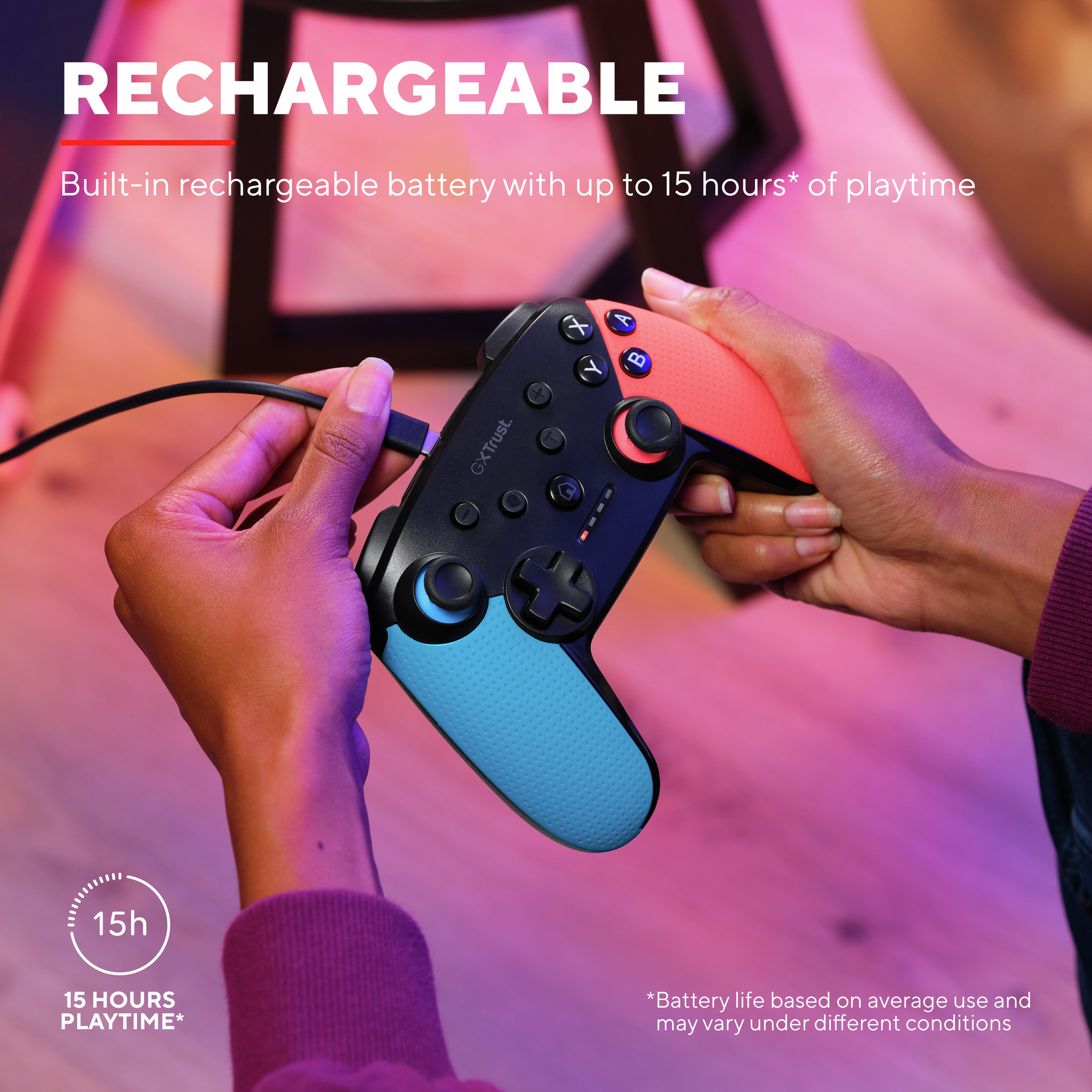 Eine Person hält einen schwarzen und farbigen Gamecontroller. Ein Ladekabel ist angeschlossen.