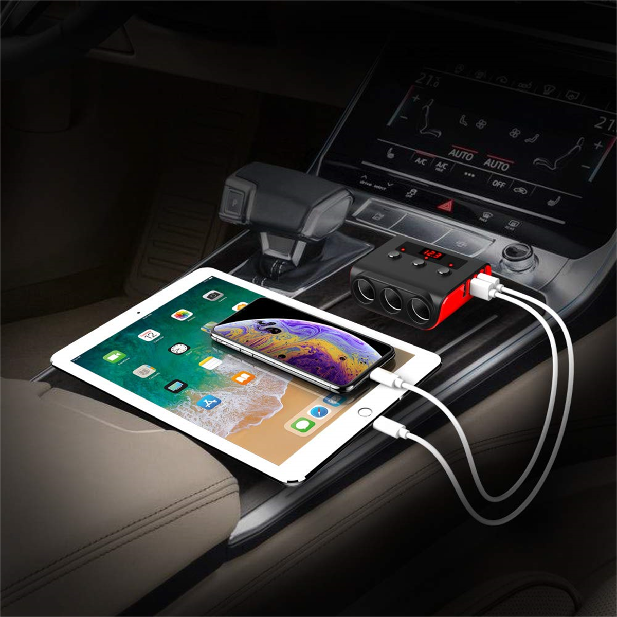 Autoinnenraum mit Tablet, Telefon und Netzteil. Weiße Kabel und ein schwarzer Adapter.