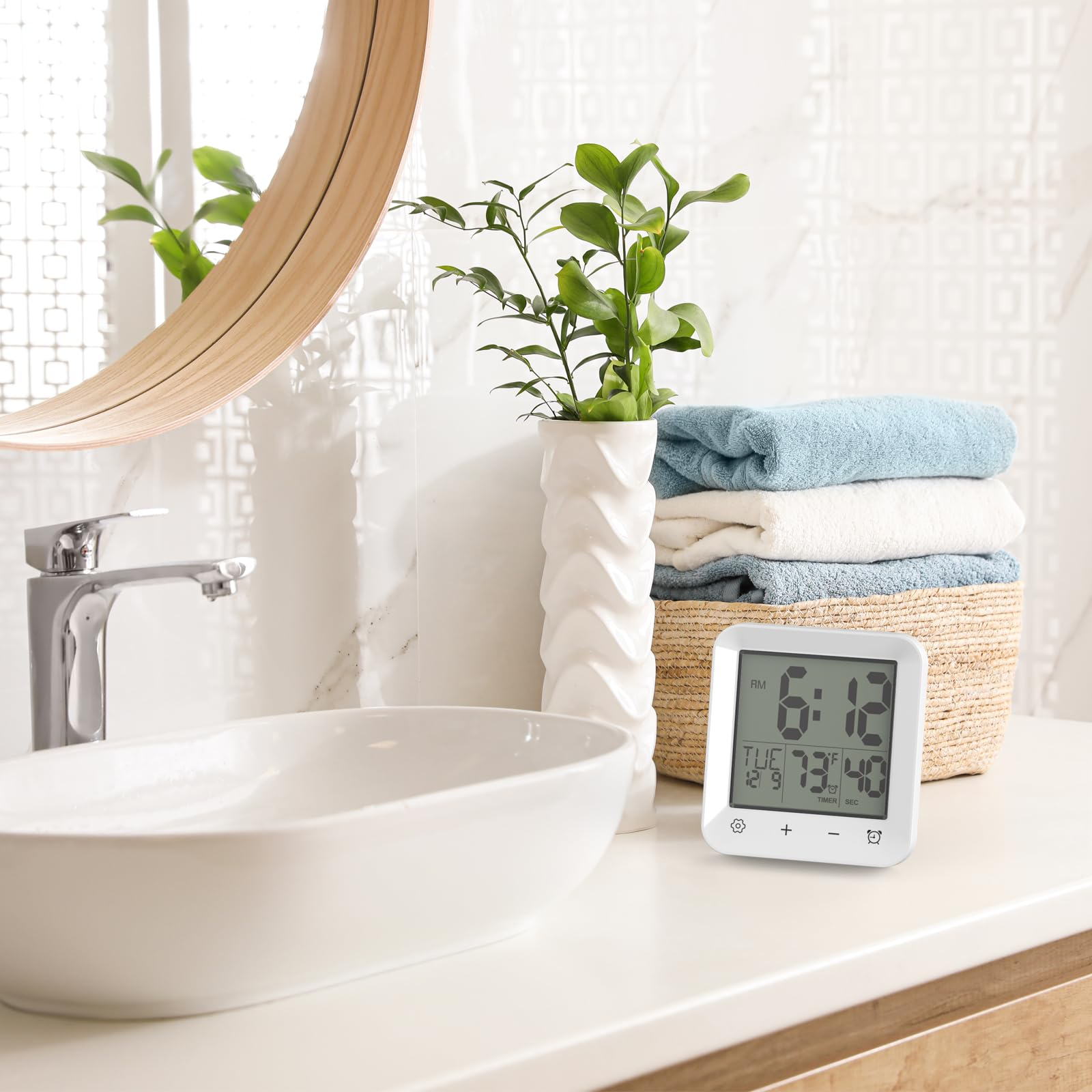 Badezimmer mit Waschbecken, Spiegel, Vase mit Pflanze, Uhr und Handtüchern.