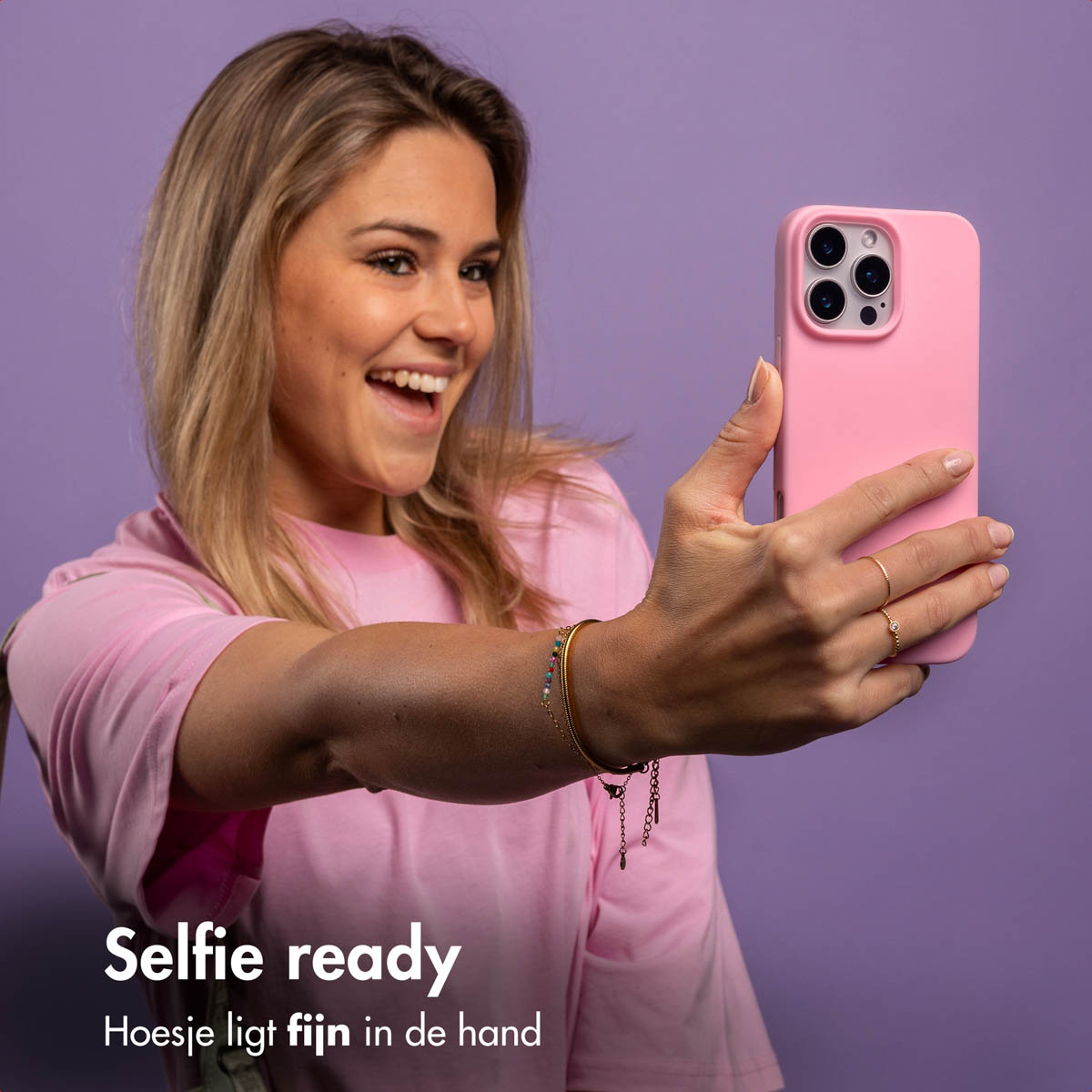 Vrouw maakt selfie met roze telefoonhoes. Tekst: Selfie klaar, ligt goed in de hand.