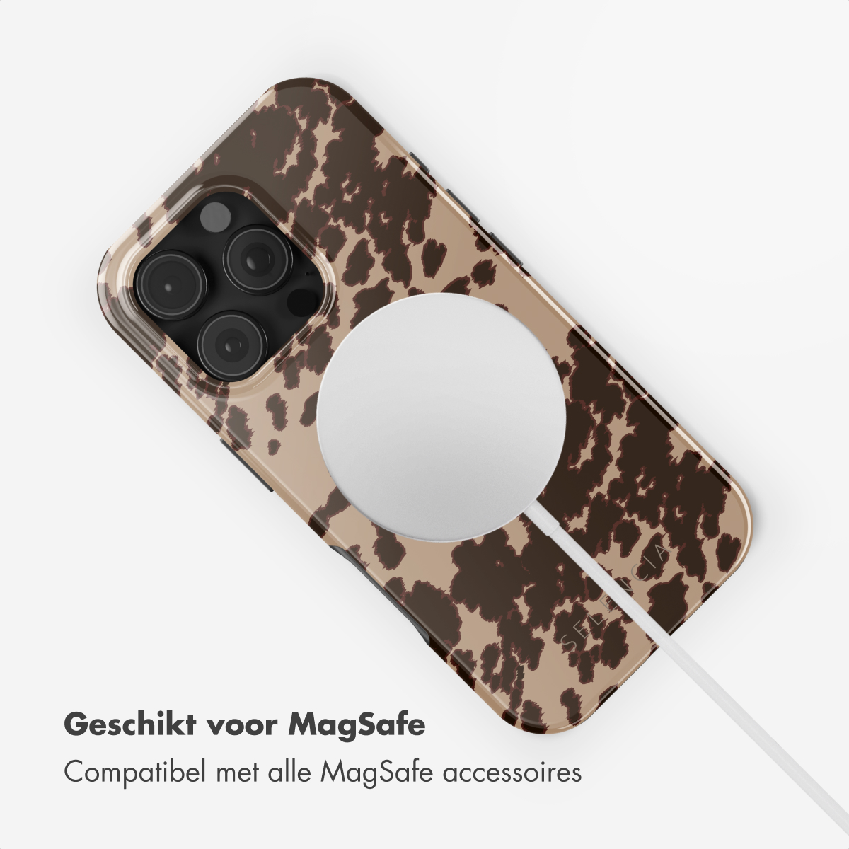 Telefoonhoesje met een bruine en beige koeienprint. Een witte MagSafe-oplader is bevestigd.