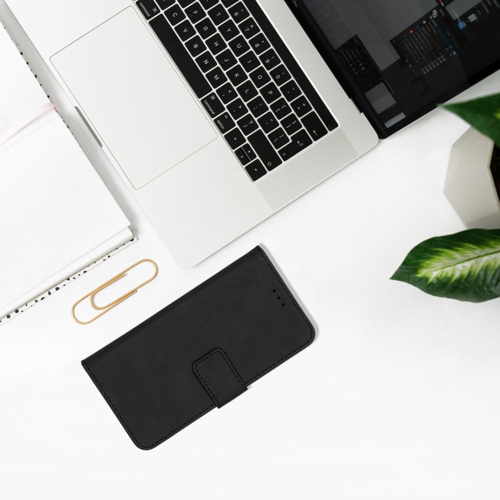 Un ordinateur portable et une coque de téléphone noire sont posés sur un bureau blanc.