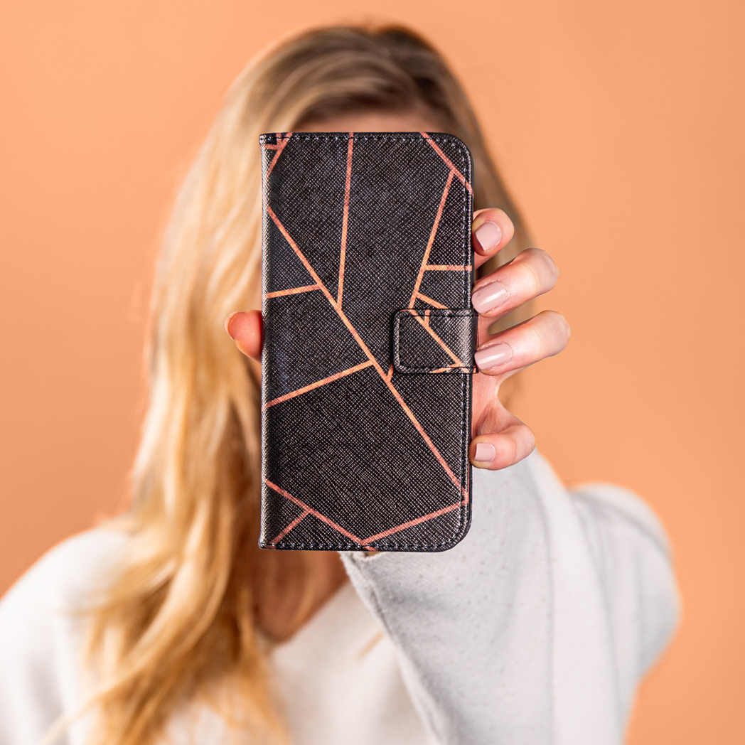 Vrouw houdt een telefoonhoes voor haar gezicht. De hoes heeft een patroon.
