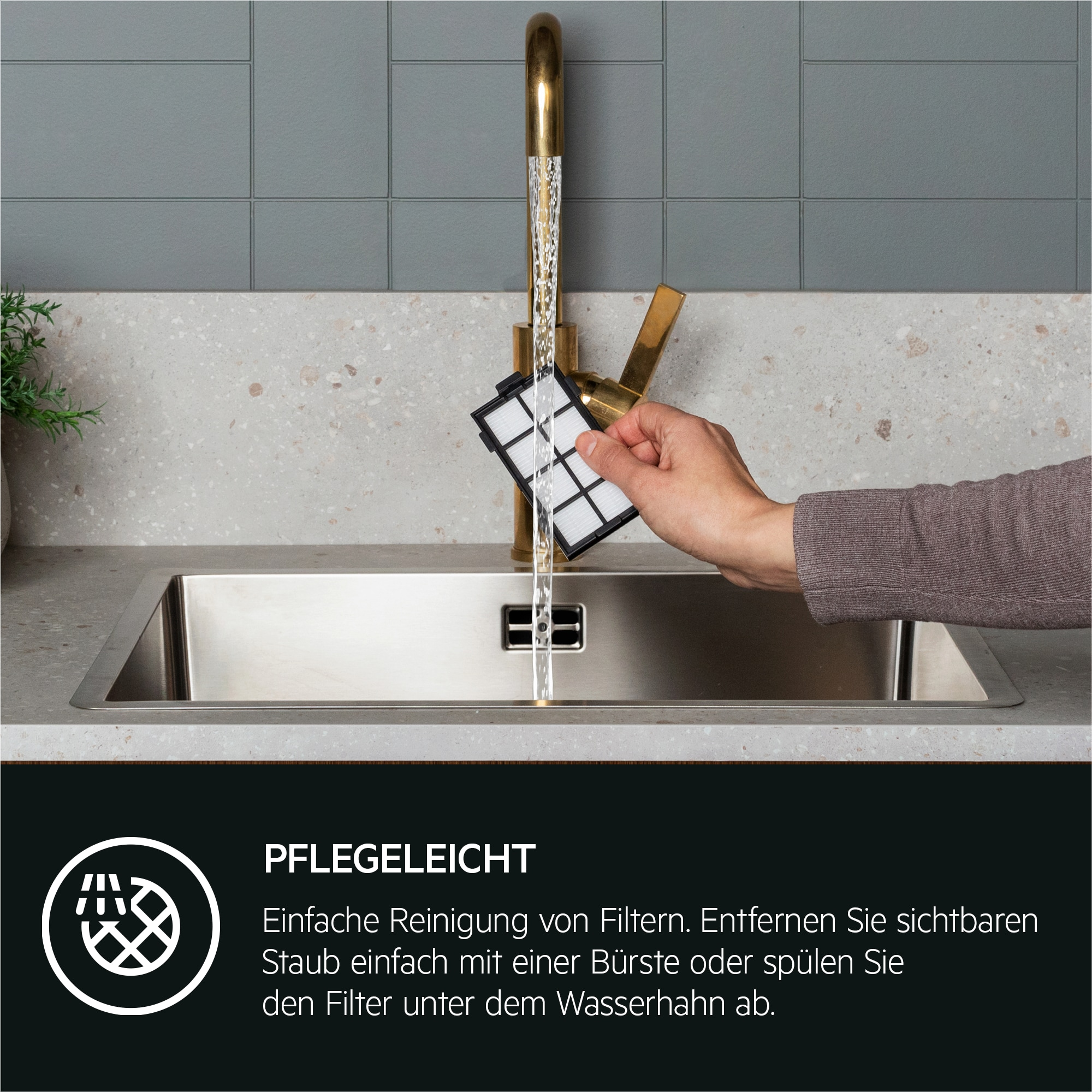 Eine Hand spült einen Filter unter einem Wasserhahn in einem Küchenbecken ab.
